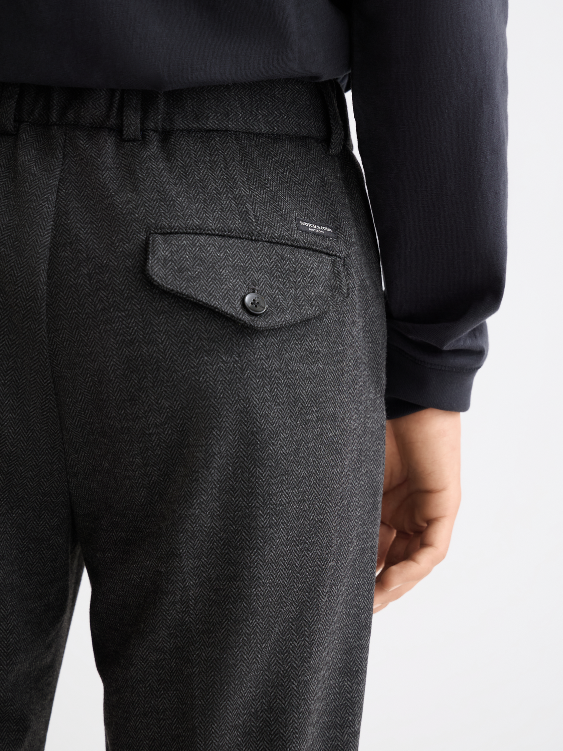 Scotch & Soda Finch tapered-fit pants in dark fabric, showing close-up of tailored waistband and slim leg design.