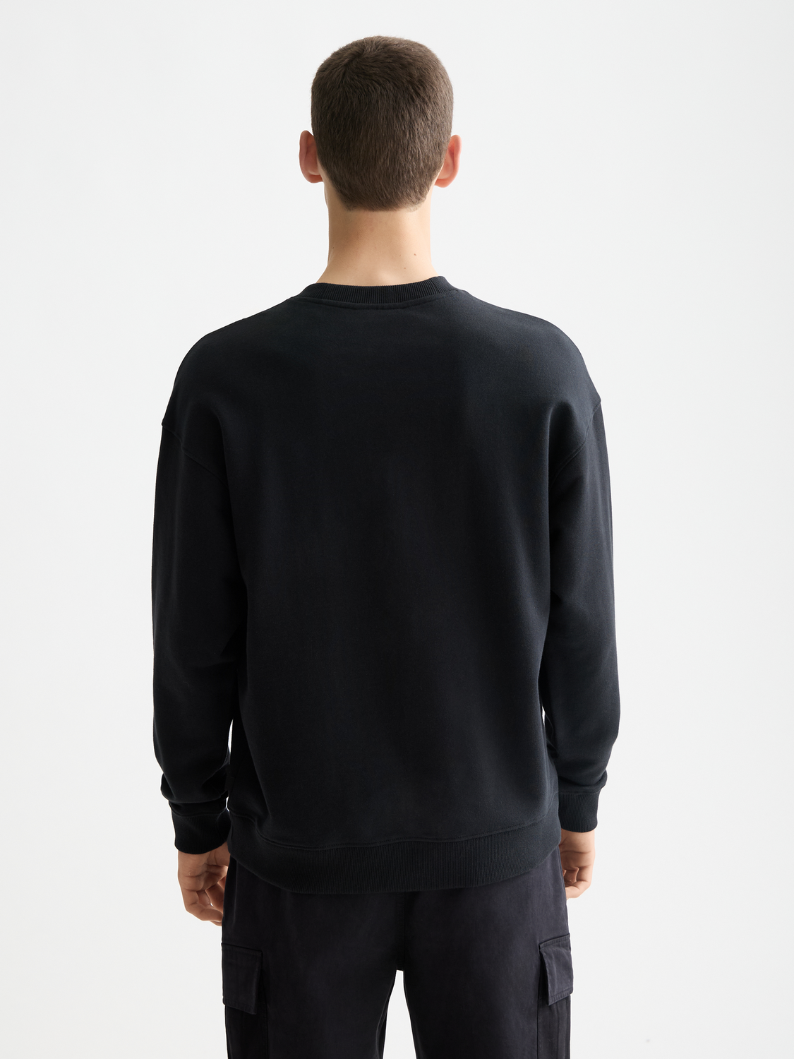 Black Scotch & Soda chest logo sweatshirt with long sleeves and ribbed cuffs, displayed on a hanger.