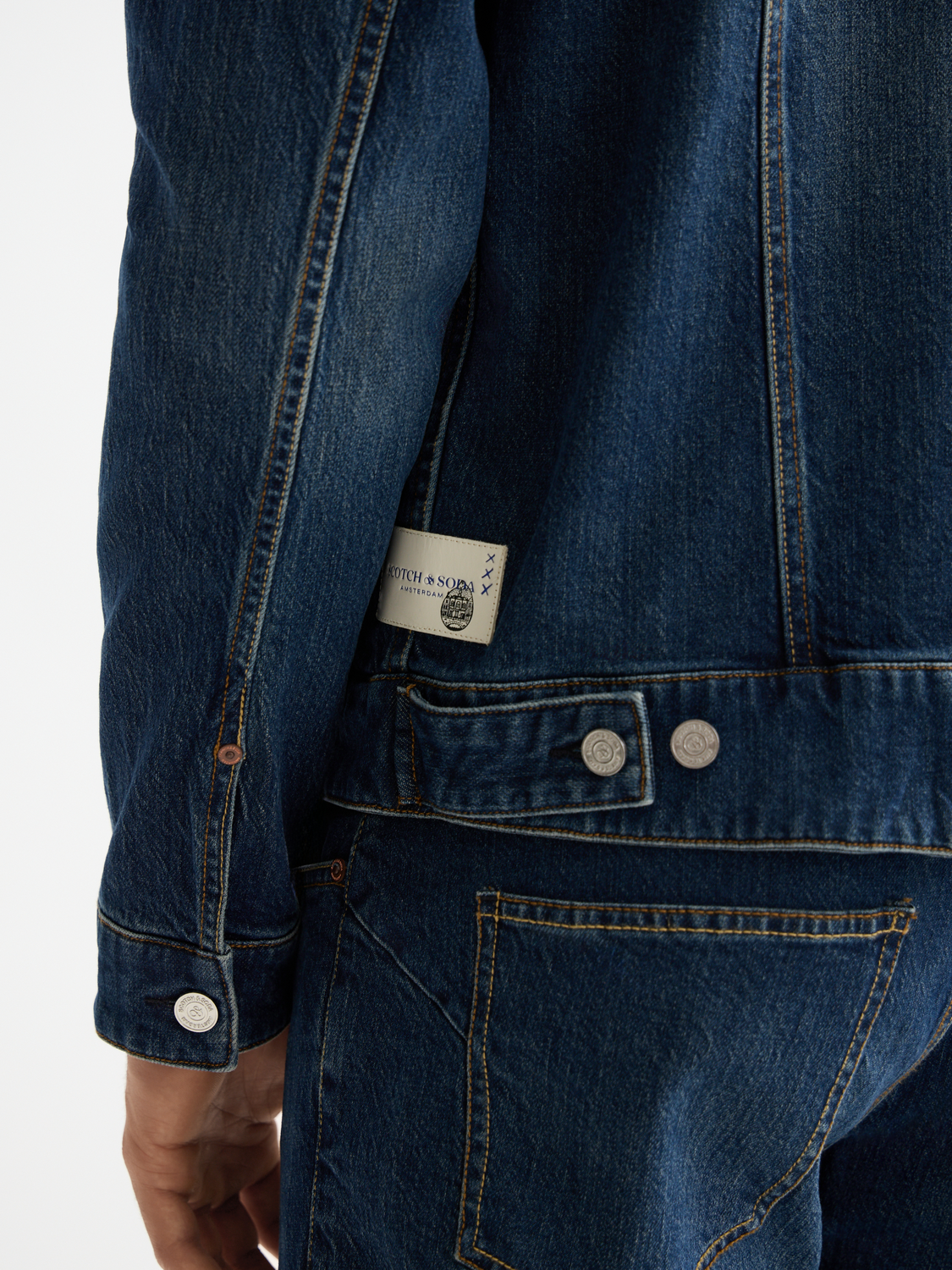 Light blue Scotch & Soda denim trucker jacket with classic collar, button front, and chest pockets, displayed on a hanger.