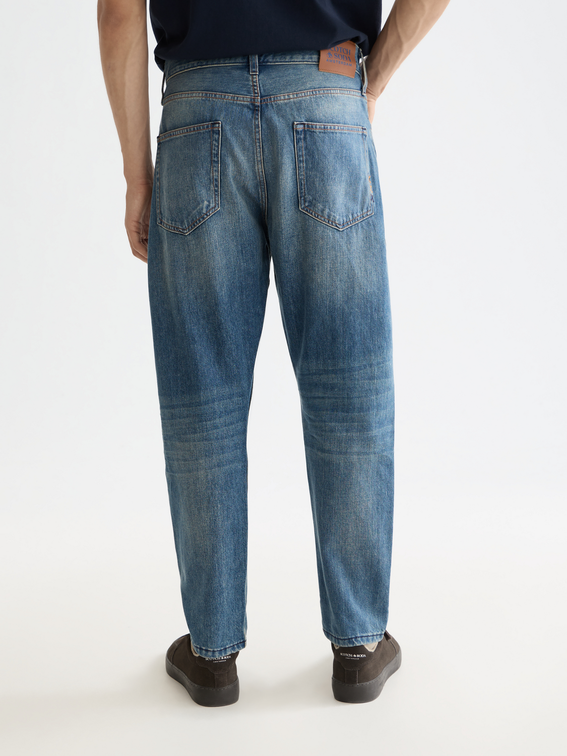 Back view of Scotch & Soda Dean tapered denim jeans showing dark wash and tailored fit on a model.