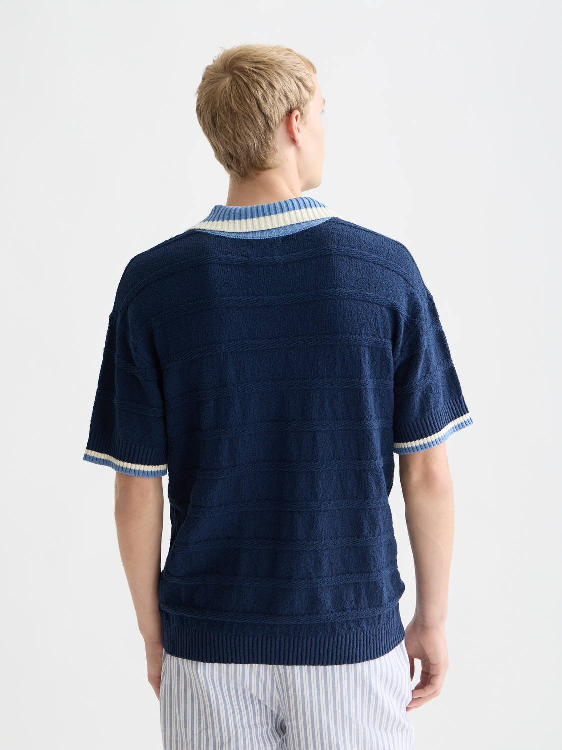 Navy knitted polo shirt by Scotch & Soda with a classic collar and textured knit fabric, shown from the back.