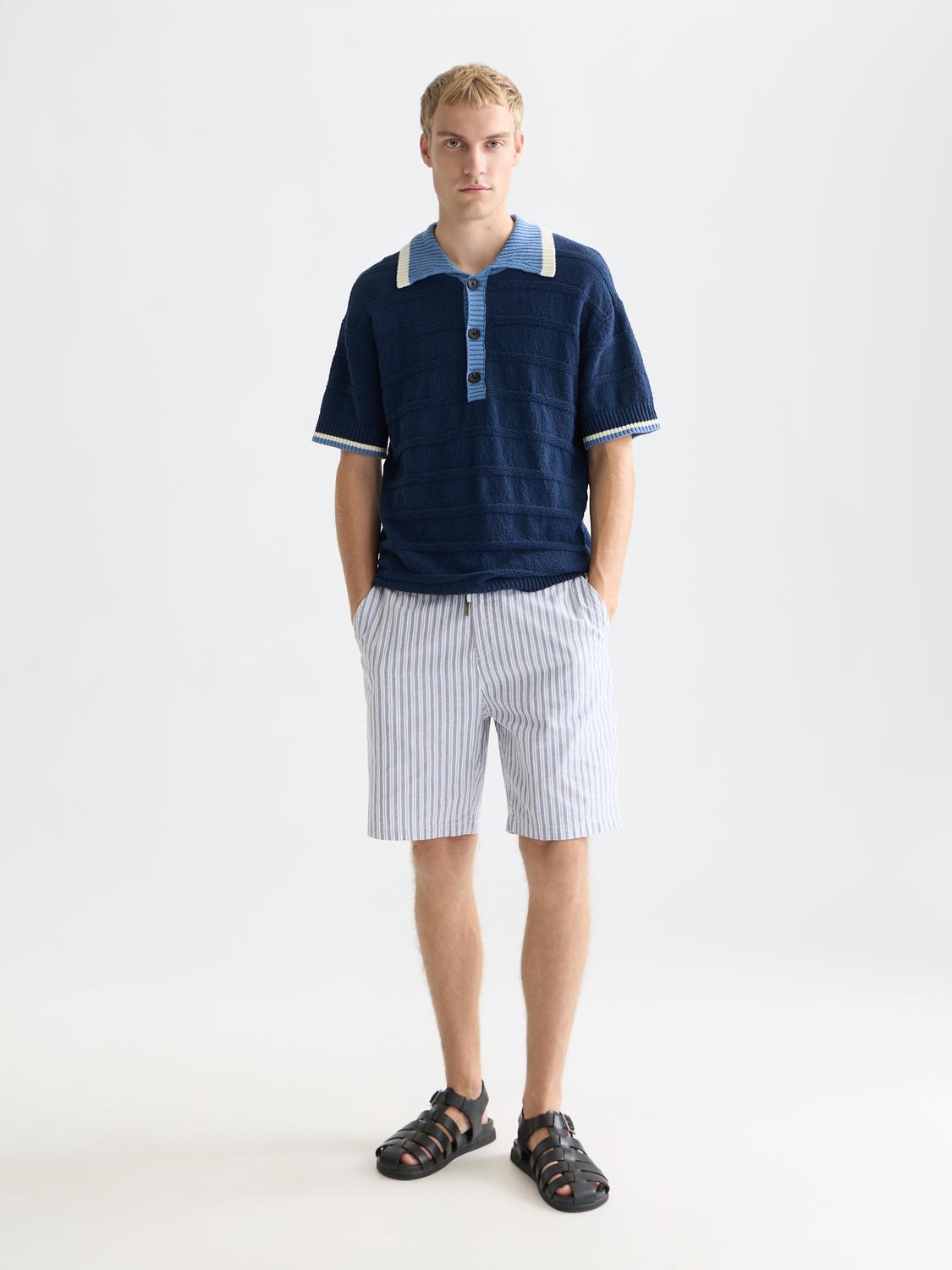 Scotch & Soda knitted polo shirt in navy with a classic collar and button placket, displayed on a neutral background.