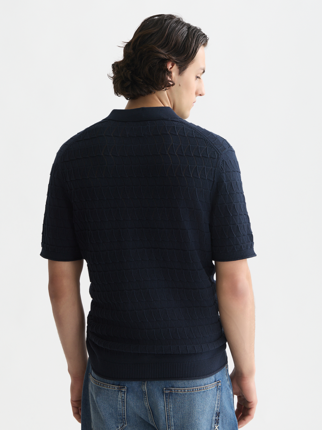 Blue knitted polo shirt from Scotch & Soda with a classic collar and ribbed cuffs, displayed from the back view.