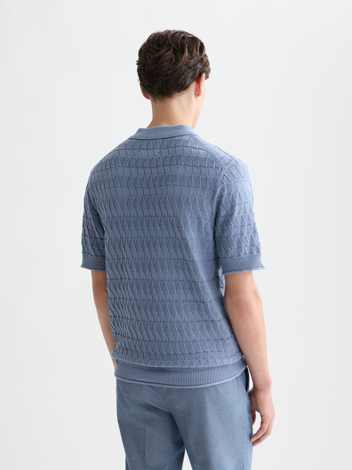 Blue knitted polo shirt by Scotch & Soda, featuring a collar and textured fabric, shown from the back.