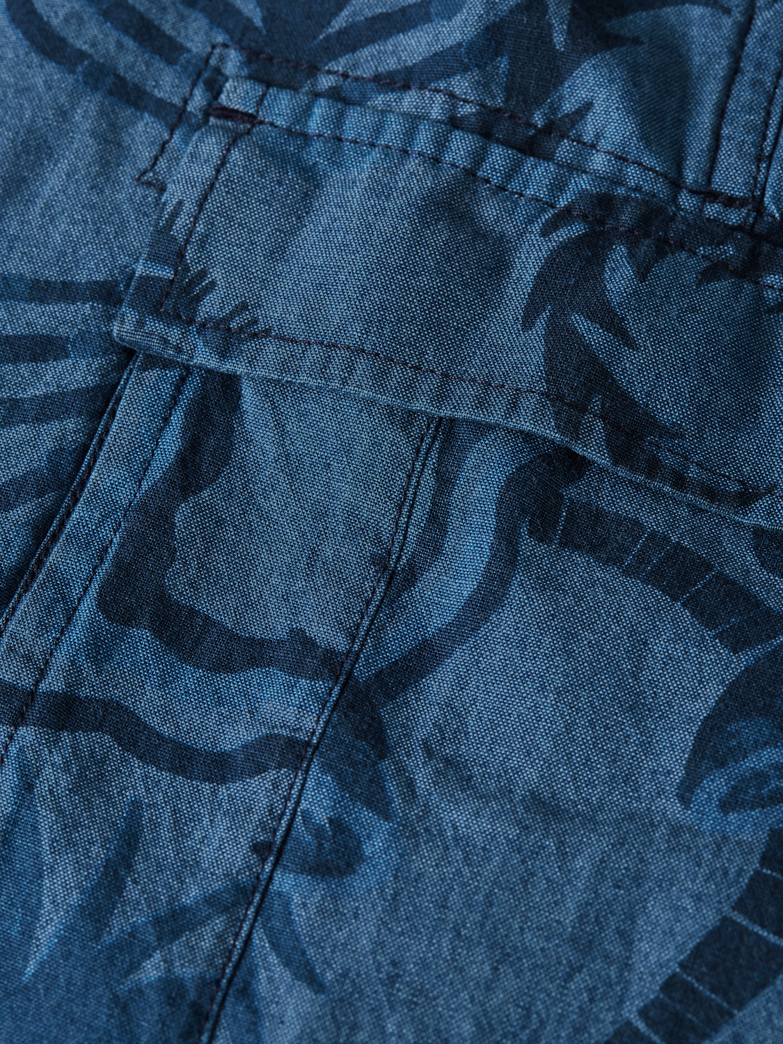Pair of Scotch & Soda printed denim cargo shorts with multiple pockets and a relaxed fit, shown on a hanger.