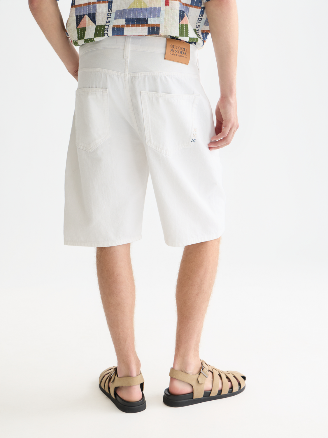 Back view of Scotch & Soda denim pitch loose-fit shorts with distressed details and rolled hems on a plain background.