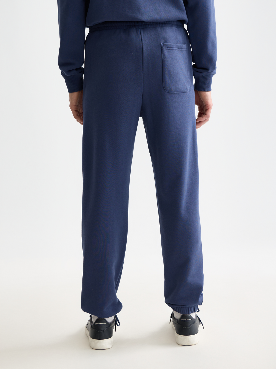 Scotch & Soda logo badge sweatpants with front and back views, casual gray athletic pants with branded logo detail.