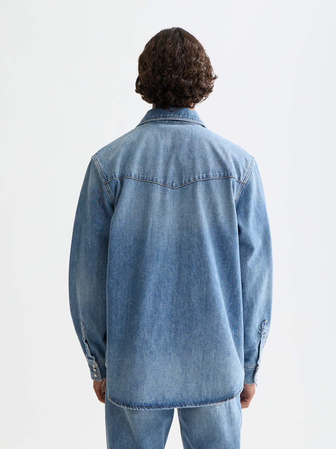 Washed denim long-sleeve shirt by Scotch & Soda, showing front view with button-down design and classic denim texture.