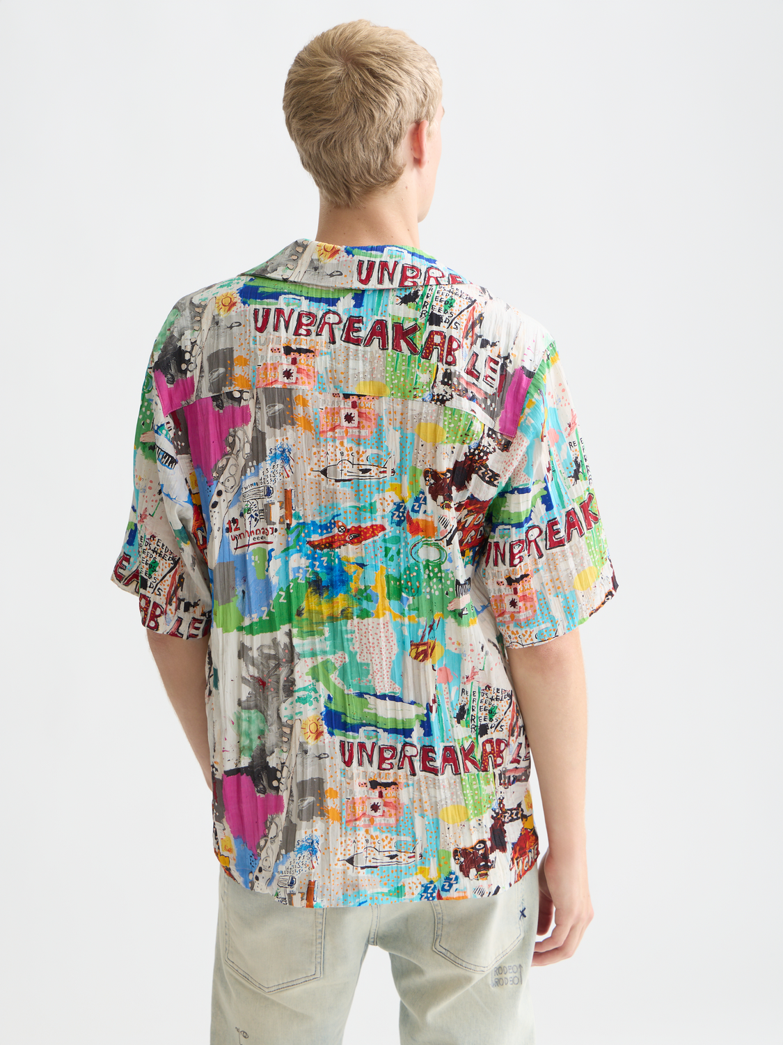 Short-sleeved shirt by Scotch & Soda featuring a Basquiat print, displayed from the back with vibrant artwork on fabric.
