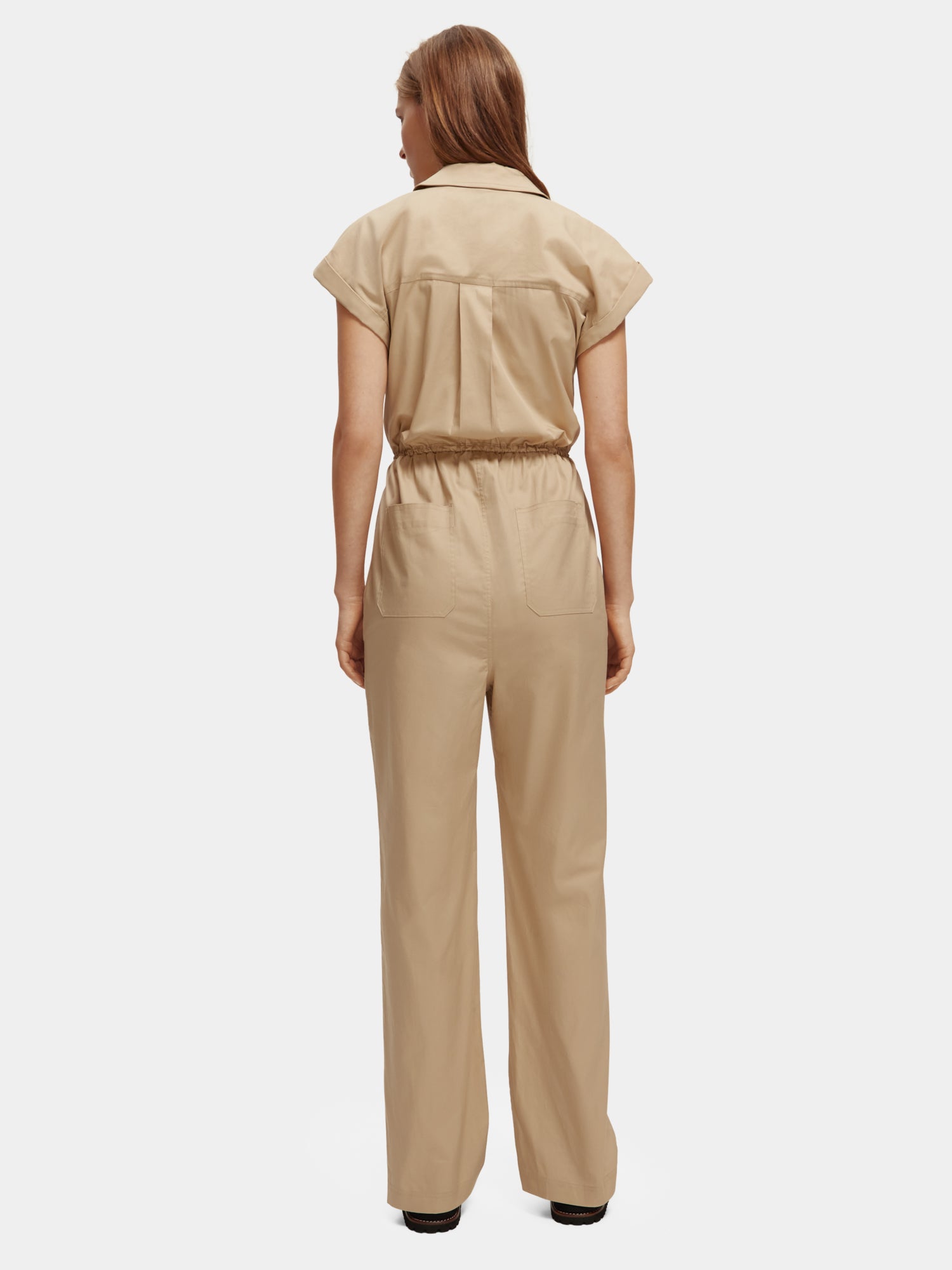 SCOTCH & SODA military jumpsuit with front zipper, multiple pockets, and belt, shown from the back in a casual style.
