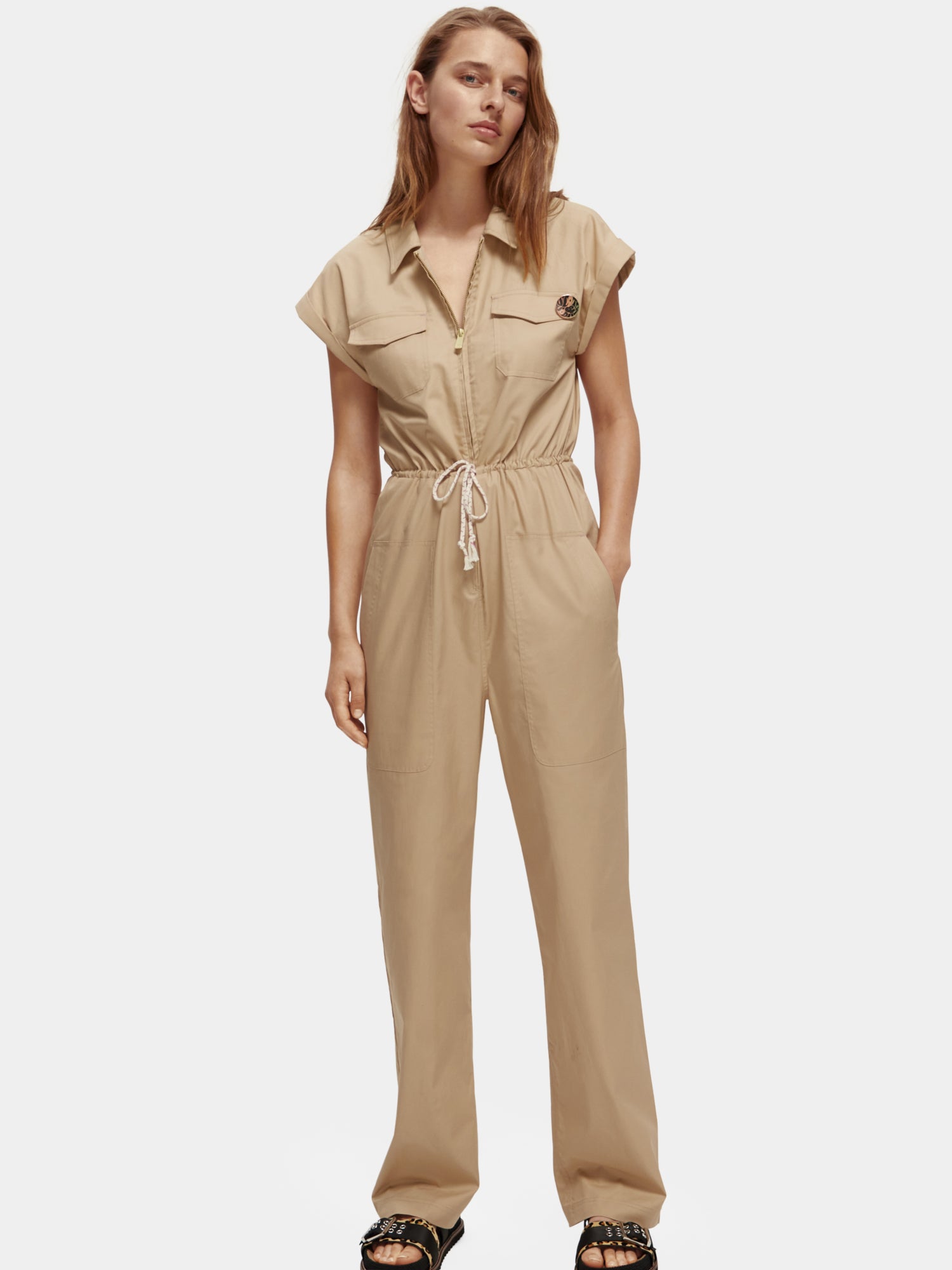 Military jumpsuit by Scotch & Soda, featuring a structured design with pockets and a utility style, shown in the product image.