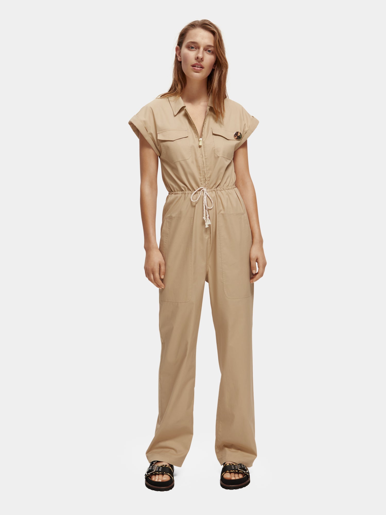 Military green jumpsuit by Scotch & Soda, featuring a front zipper, adjustable waist, and multiple pockets for a functional look.