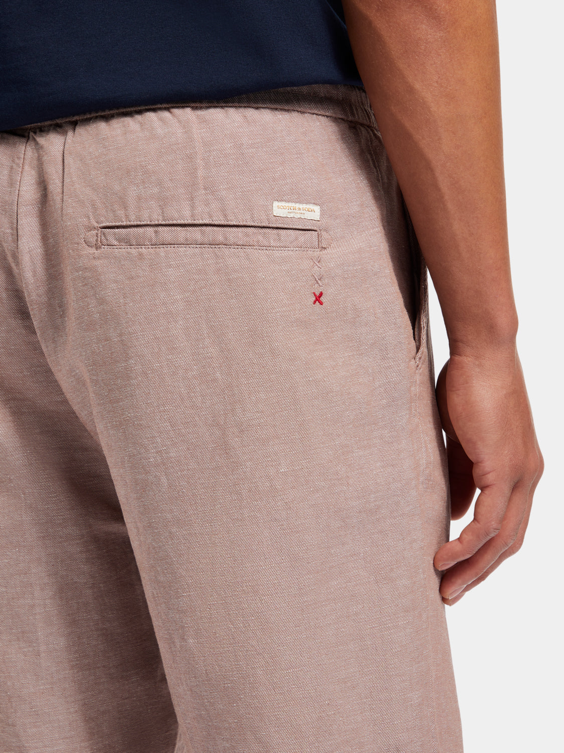 Light beige Fave cotton-linen shorts from Scotch & Soda, displayed on a hanger with subtle fabric texture visible.