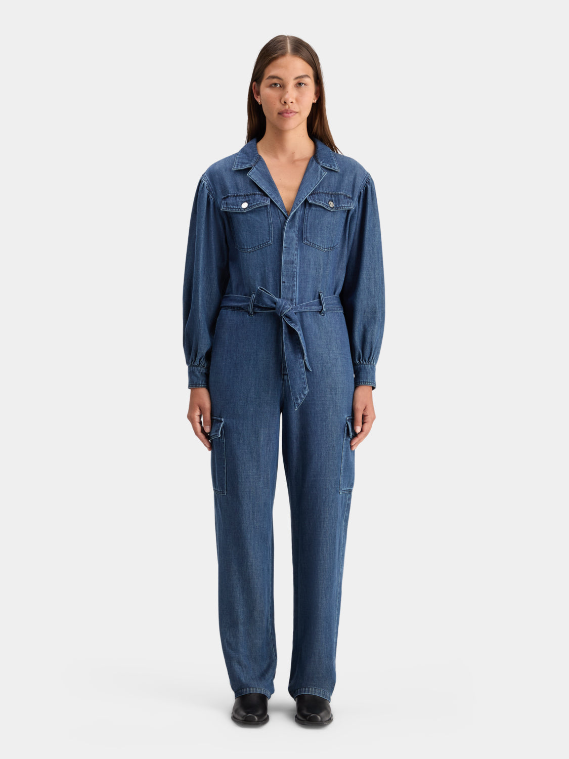 Blue denim jumpsuit by Scotch & Soda with front zipper and adjustable straps, displayed on a hanger.