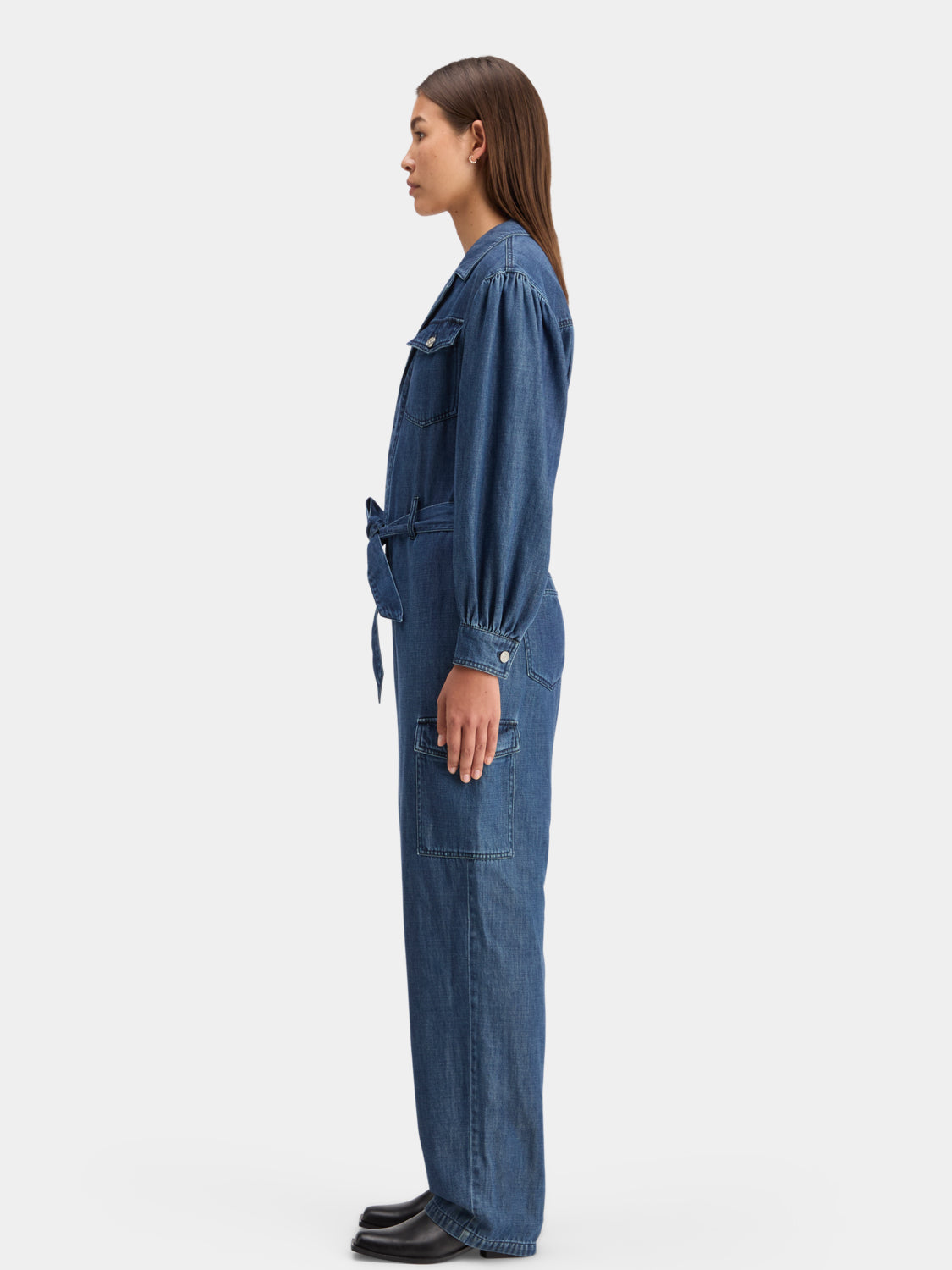Blue denim jumpsuit by Scotch & Soda with front pockets and adjustable straps, displayed on a hanger.