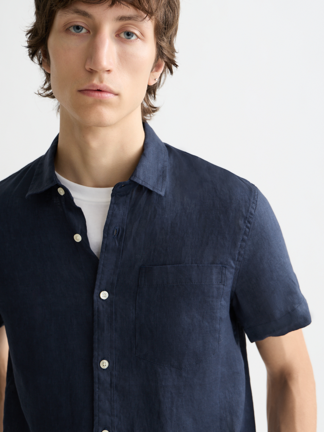 Light beige short-sleeved linen shirt from Scotch & Soda, shown with a relaxed fit and button-front design.