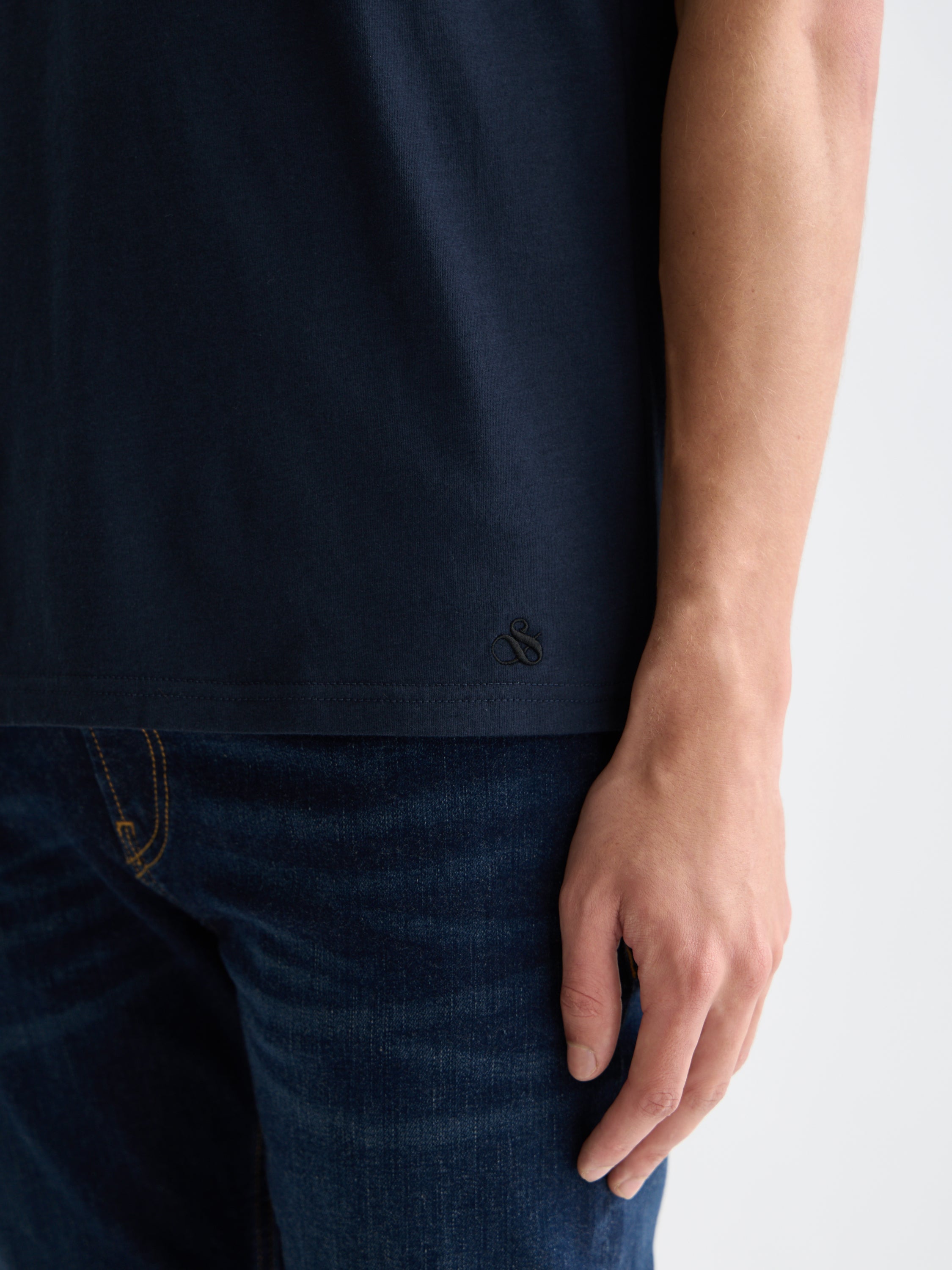 Three short-sleeve crew neck T-shirts by Scotch & Soda in neutral colors, neatly folded and stacked.