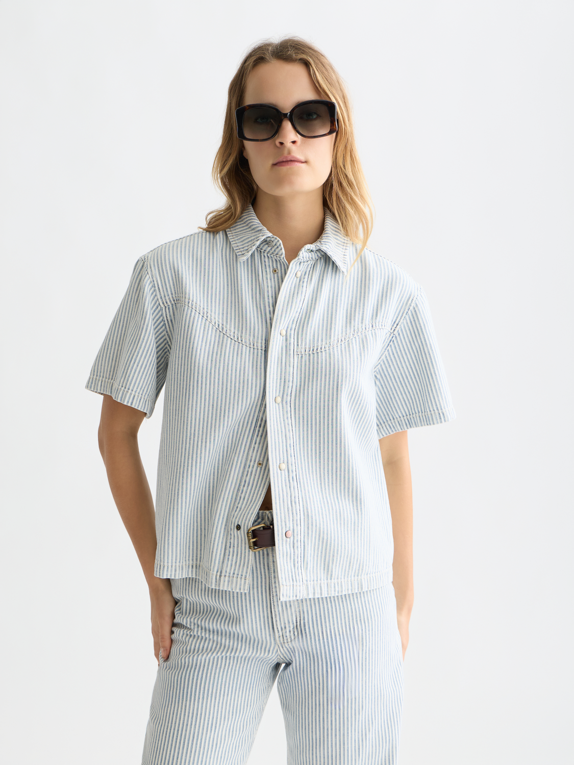 Short-sleeved denim shirt from Scotch & Soda with classic collar and button front, displayed on a model against a neutral background.