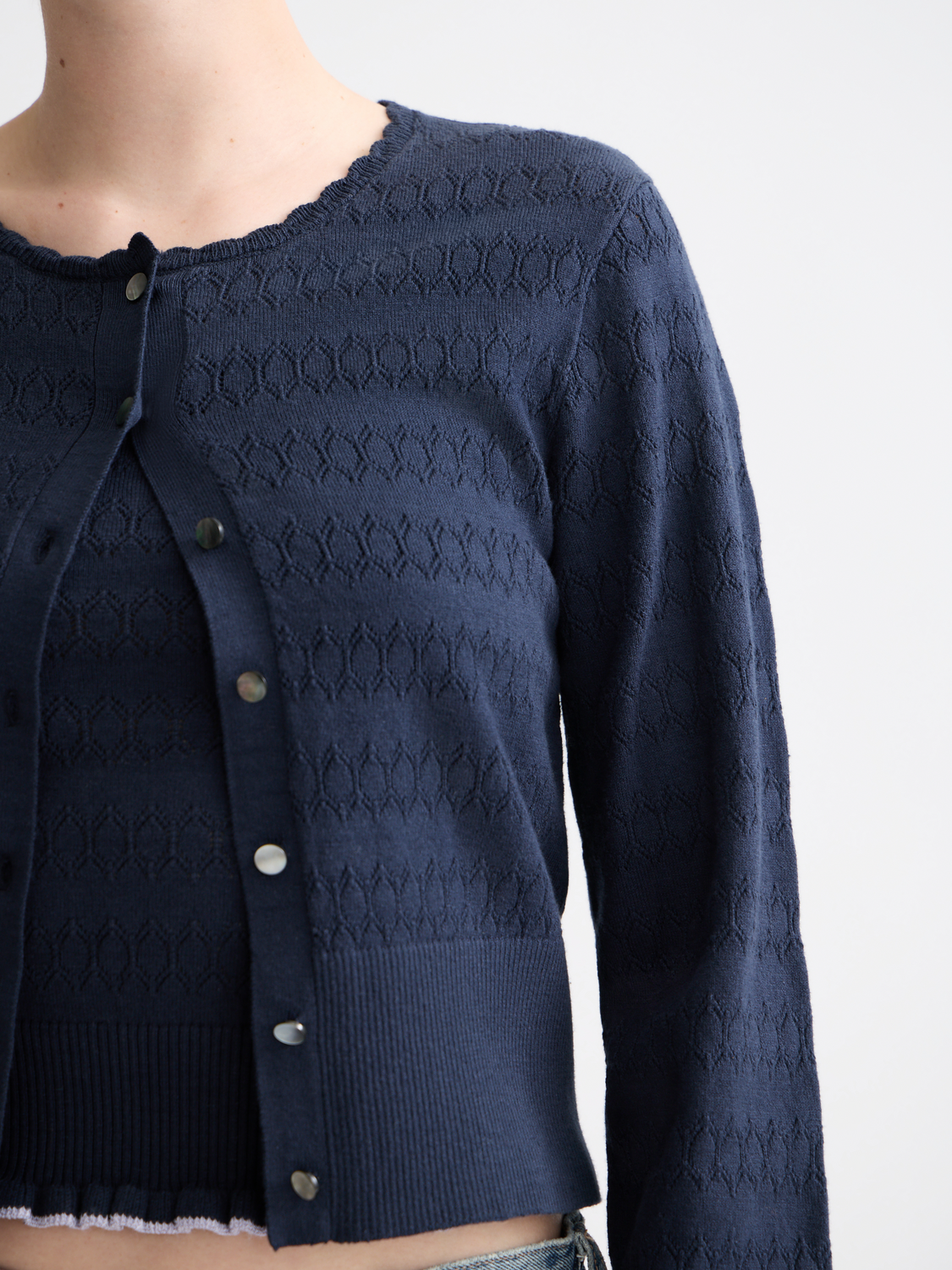 Pointelle knitted cardigan from Scotch & Soda, showcasing a soft, patterned knitwear design with long sleeves and a button-up front.