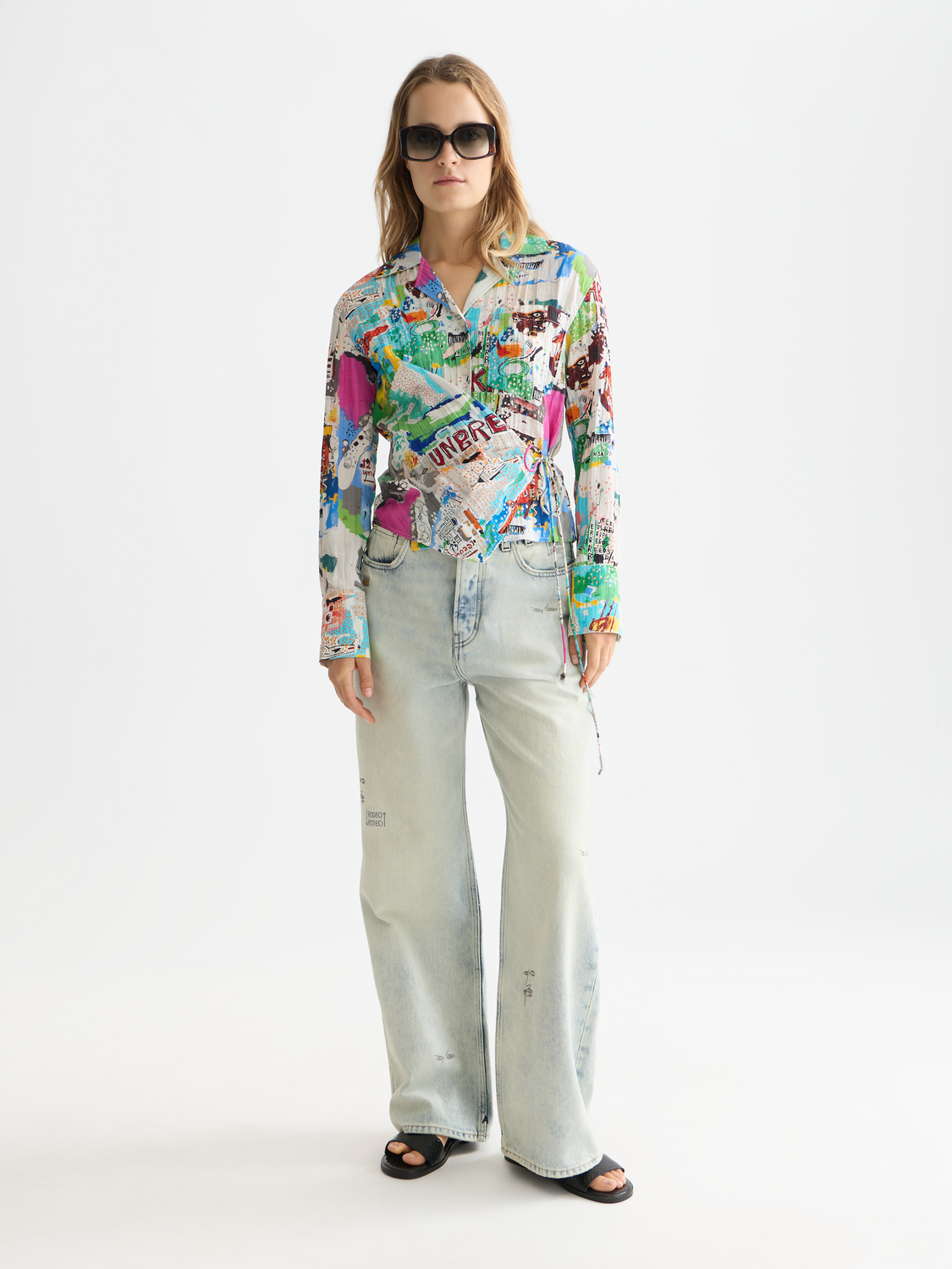 Scotch & Soda long-sleeved shirt featuring Basquiat artwork, with a button-down collar and vibrant graphic print on the front.