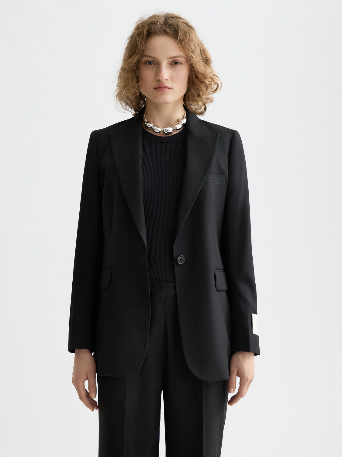 Fitted single-breasted blazer by Scotch & Soda featuring a tailored design, classic lapels, and sleek fabric in a neutral color.
