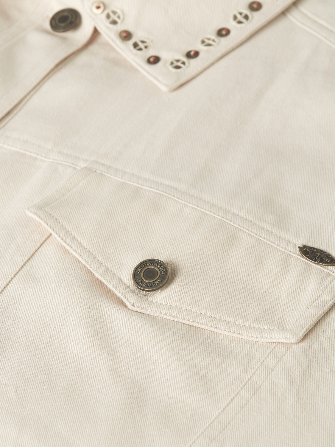 Embellished Scotch & Soda trucker jacket with decorative details and classic denim style, displayed on a hanger.