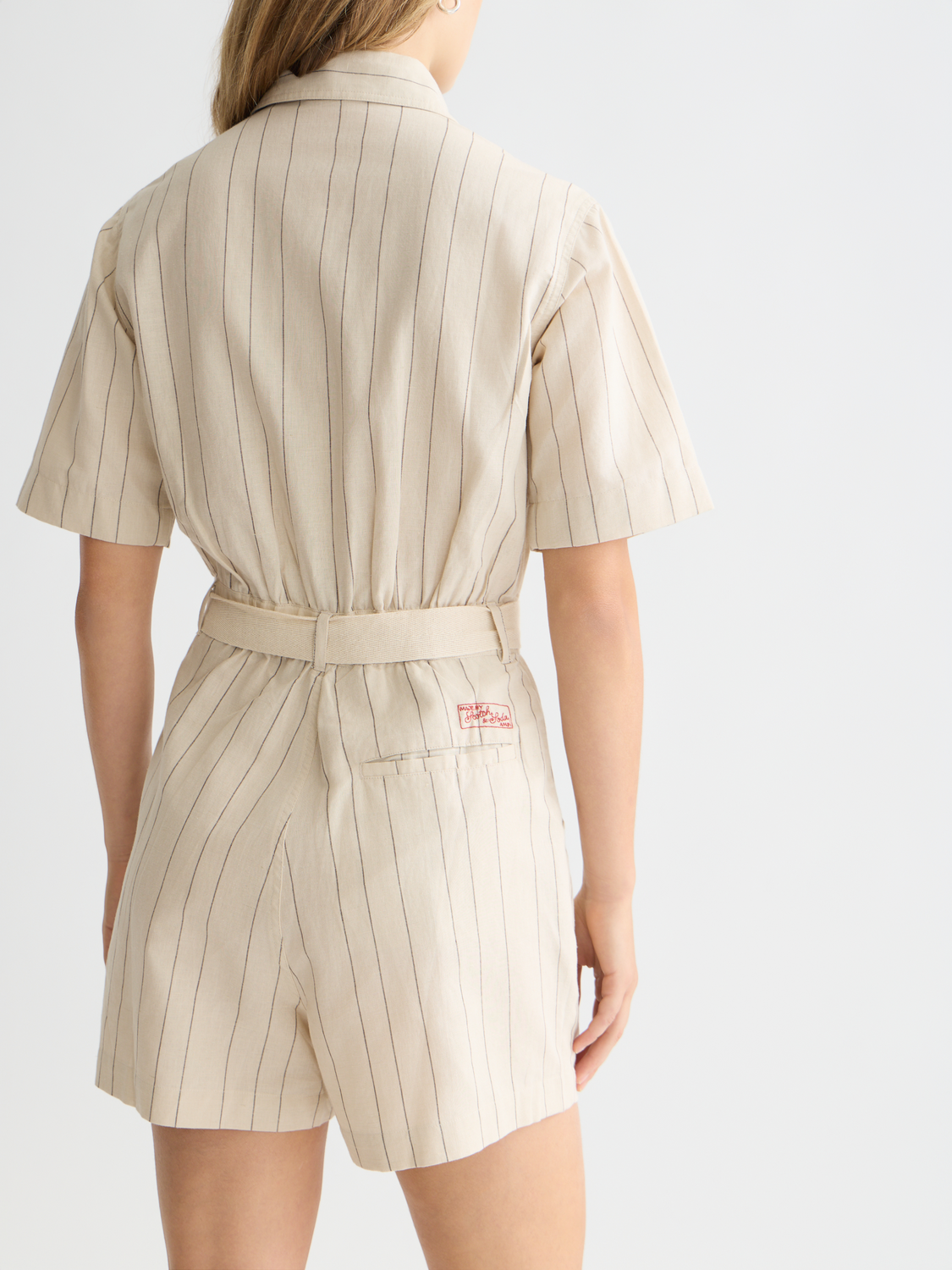 Pinstripe Scotch & Soda playsuit featuring a fitted bodice and wide-leg trousers, styled with a belt and short sleeves.