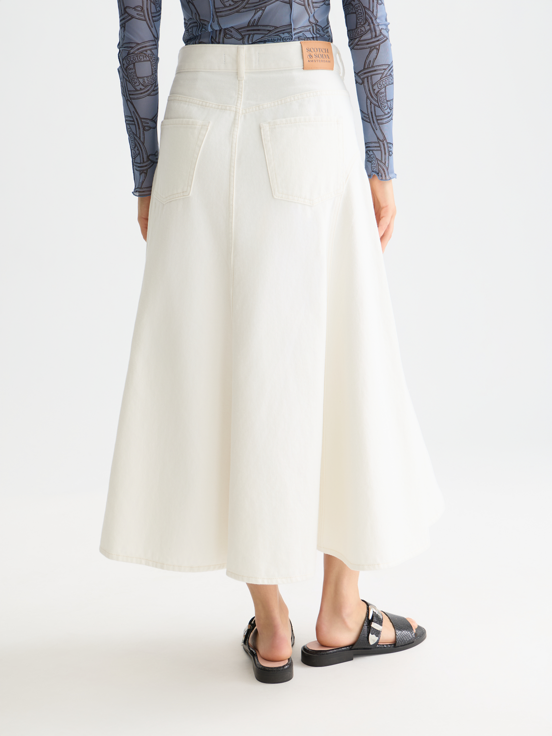 Dark wash denim maxi skirt by Scotch & Soda with a flowing silhouette and back slit, styled with a casual, trendy look.