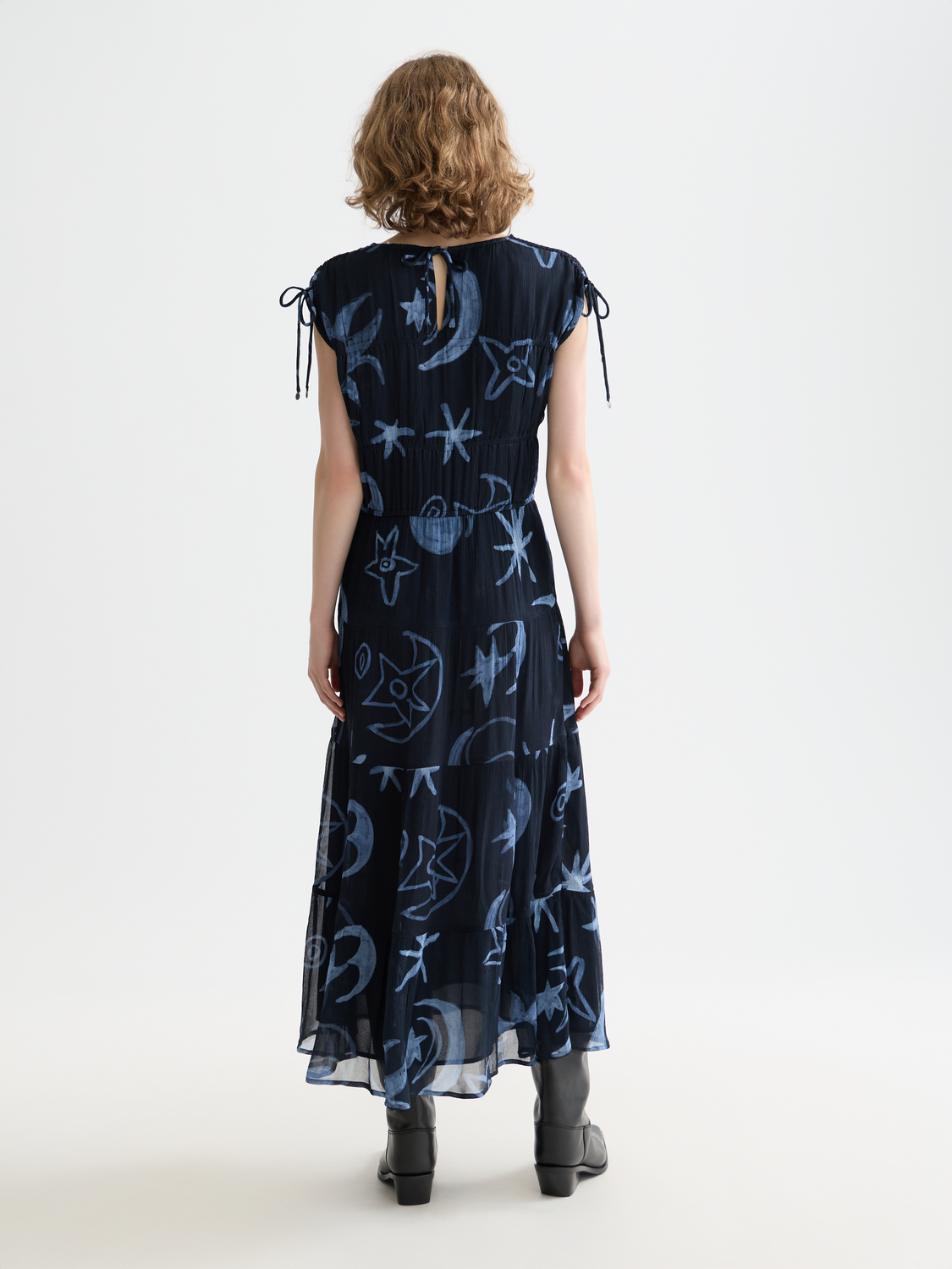 Black gathered midi dress by Scotch & Soda with a fitted waist and flowing skirt, showcased on a model.