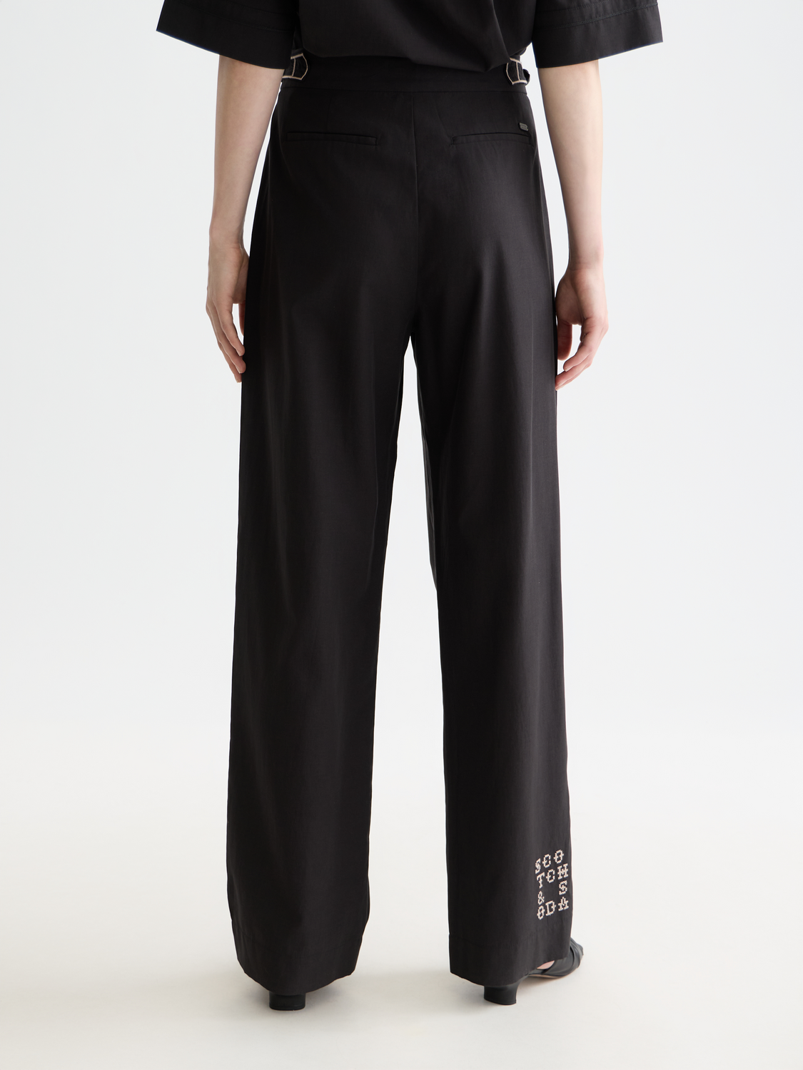 SCOTCH & SODA Quinn pleated pants in dark fabric, front view showing tailored waistband and classic pleats.