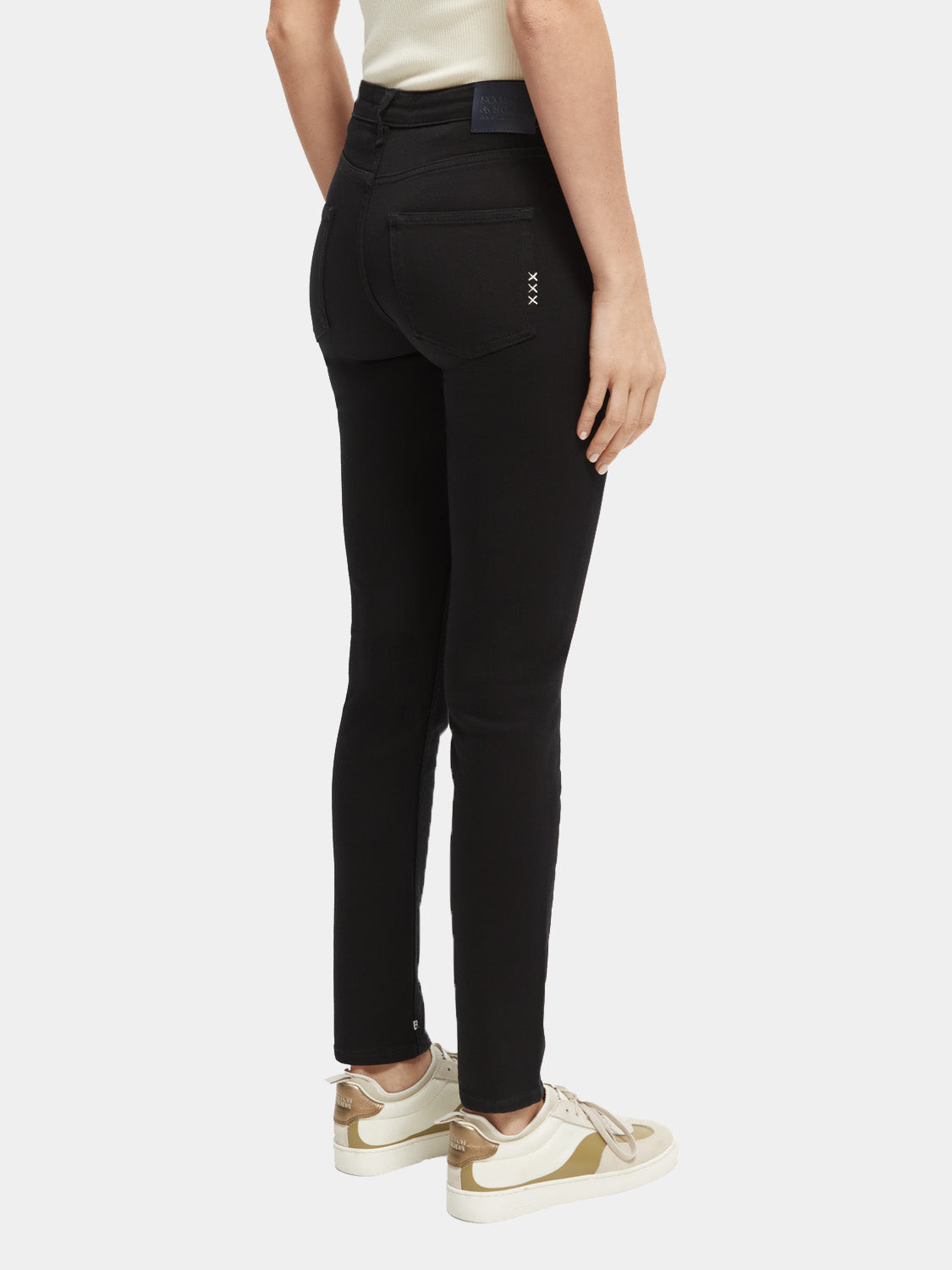 Skinny fit denim jeans by Scotch & Soda displayed on a hanger, showcasing dark wash and sleek silhouette.
