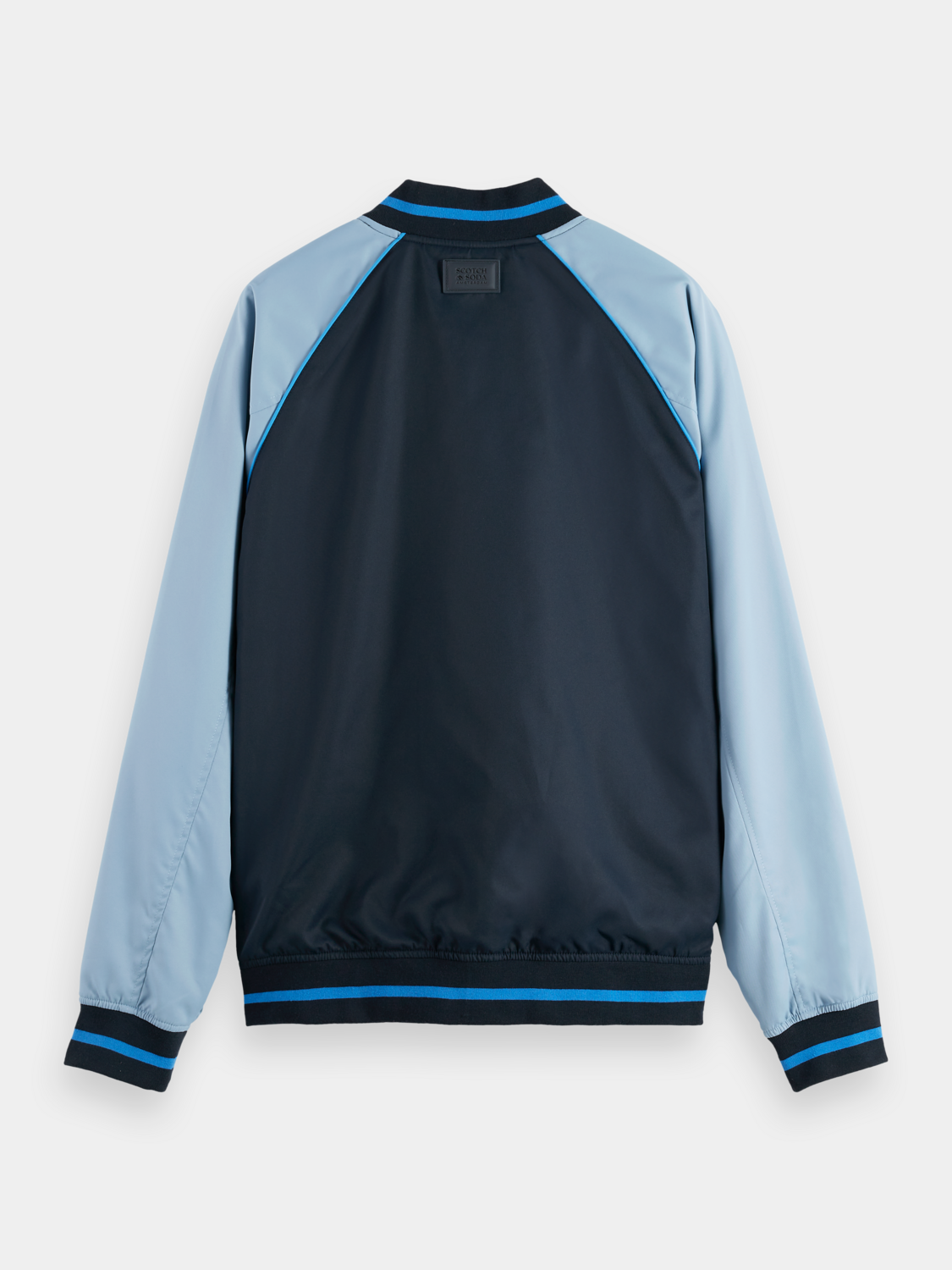 Reversible SCOTCH & SODA bomber jacket with black and patterned sides, shown on a hanger with front view.