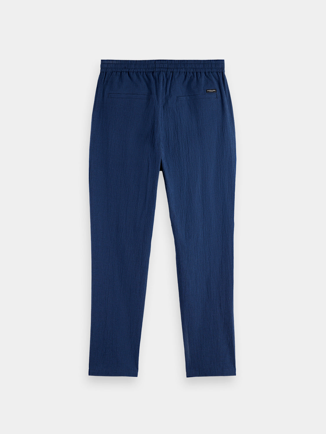 Black Scotch & SODA Finch tapered-fit pants displayed on a hanger showing the slim cut and tailored design.