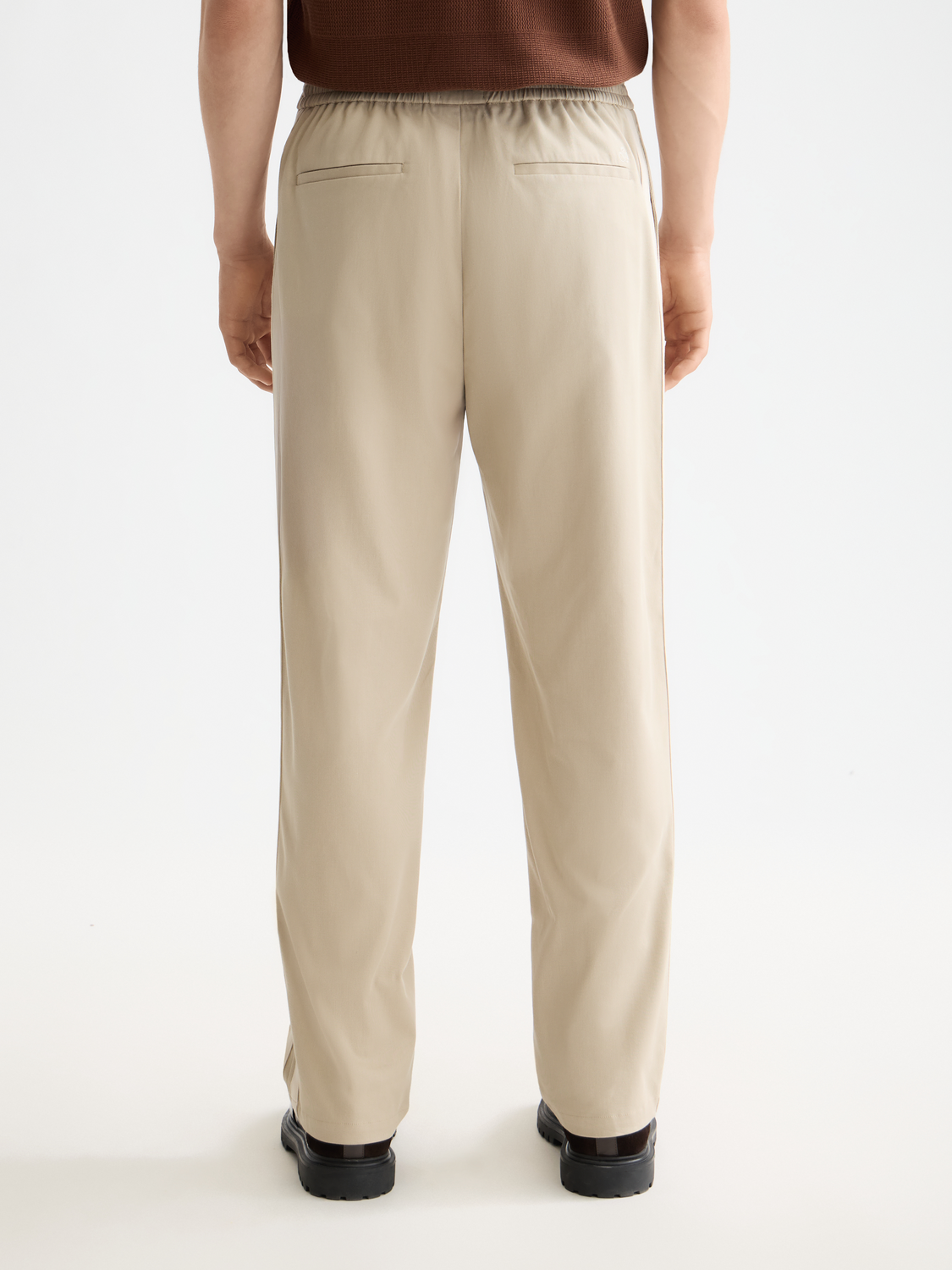 Back view of Scotch & Soda pleated straight-fit jogger pants in neutral color, featuring a relaxed fit and subtle pleats.
