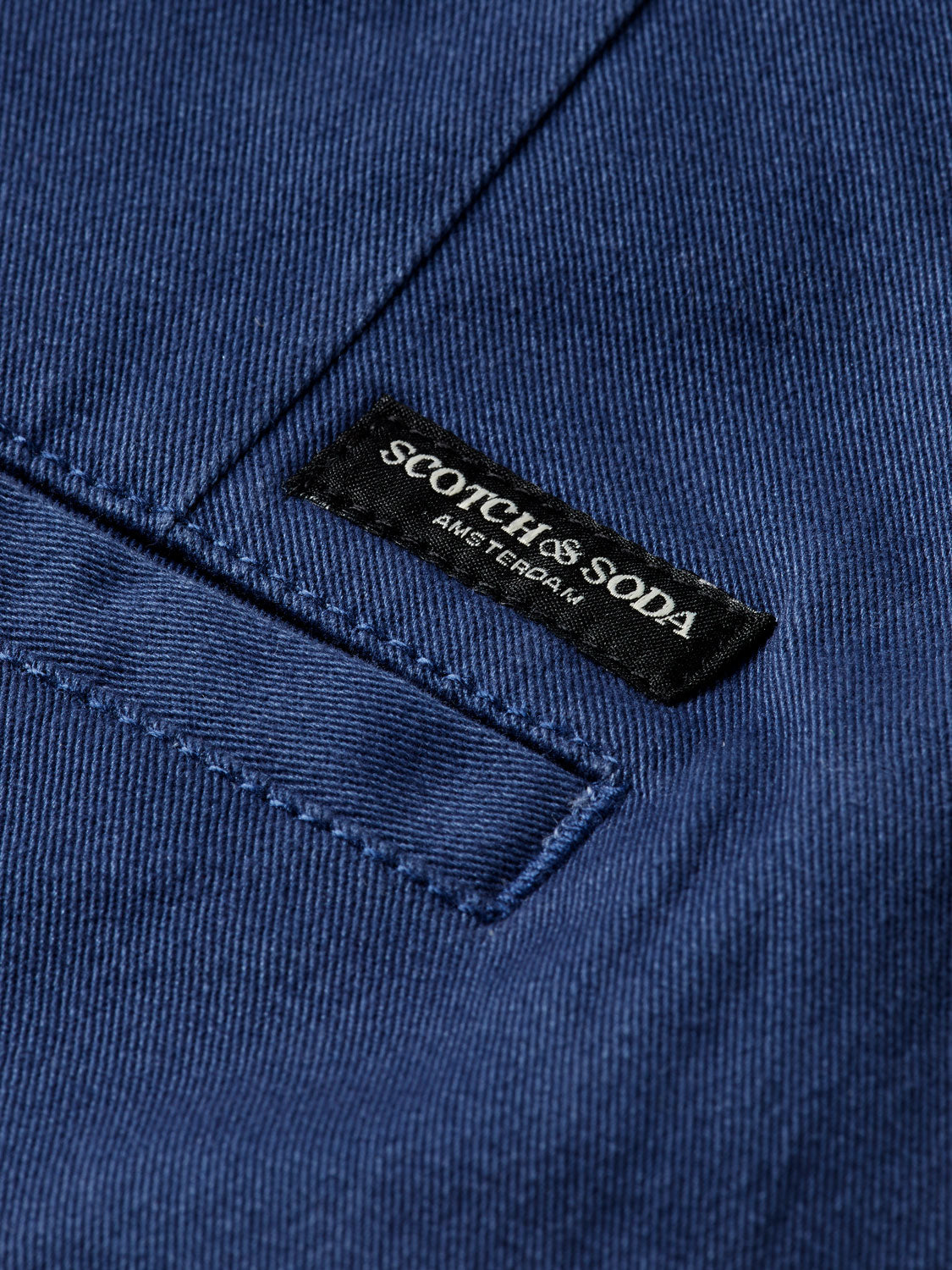 Slim-fit Mott chinos from Scotch & Soda, showing beige pants with front pockets and belt loops on a plain background.