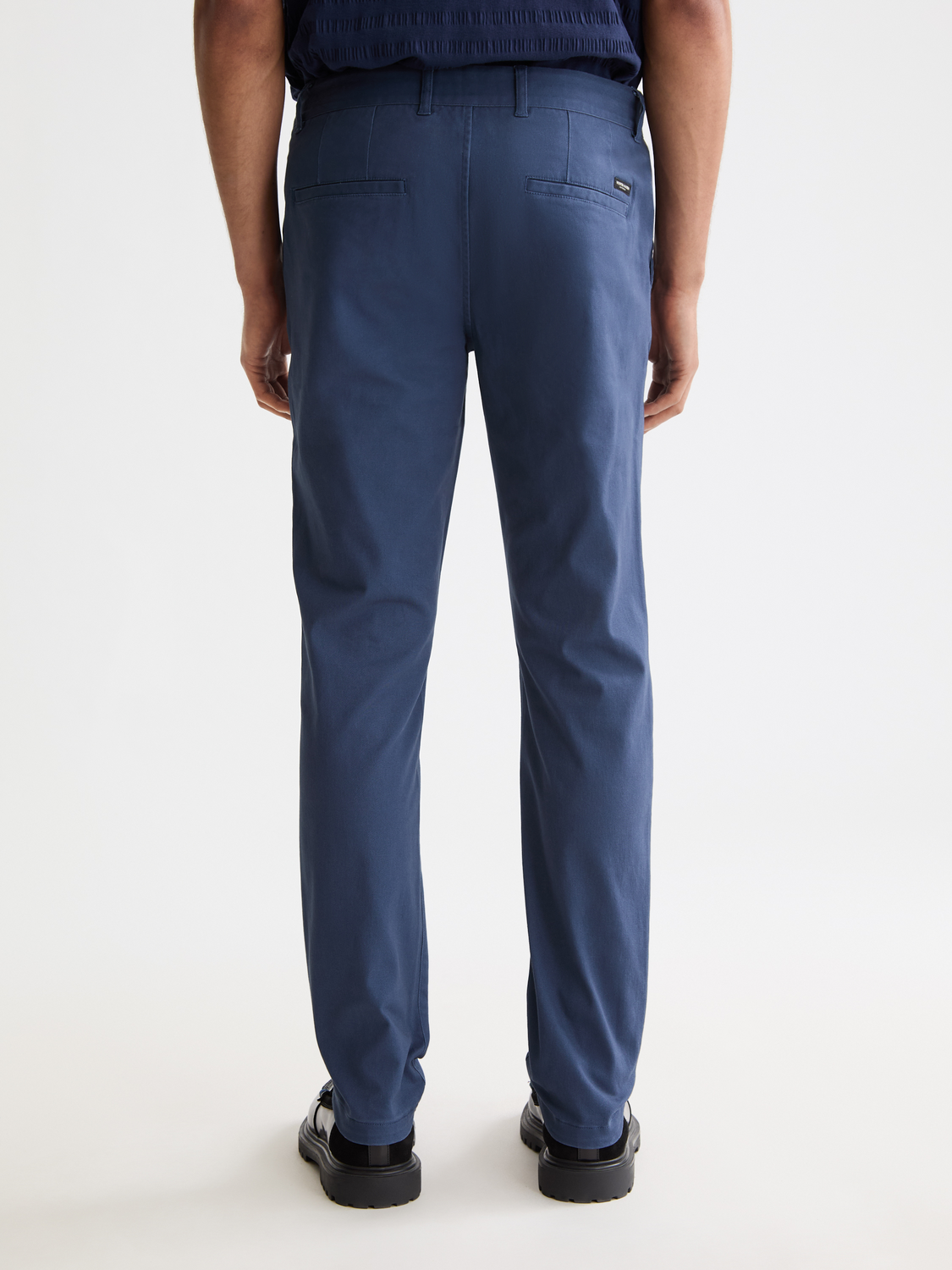 Back view of SCOTCH & SODA Mott slim-fit chinos pants in dark fabric, showcasing tailored fit and clean stitching.