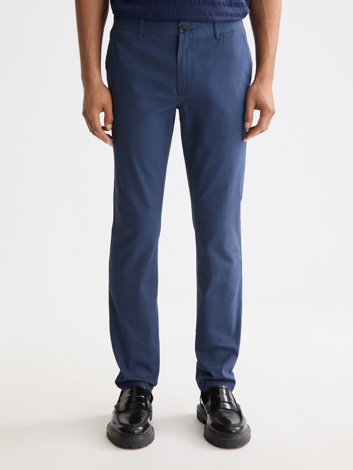 Scotch & Soda Mott slim-fit chinos pants in a dark color, featuring a close-up of the front with pockets and belt loops.