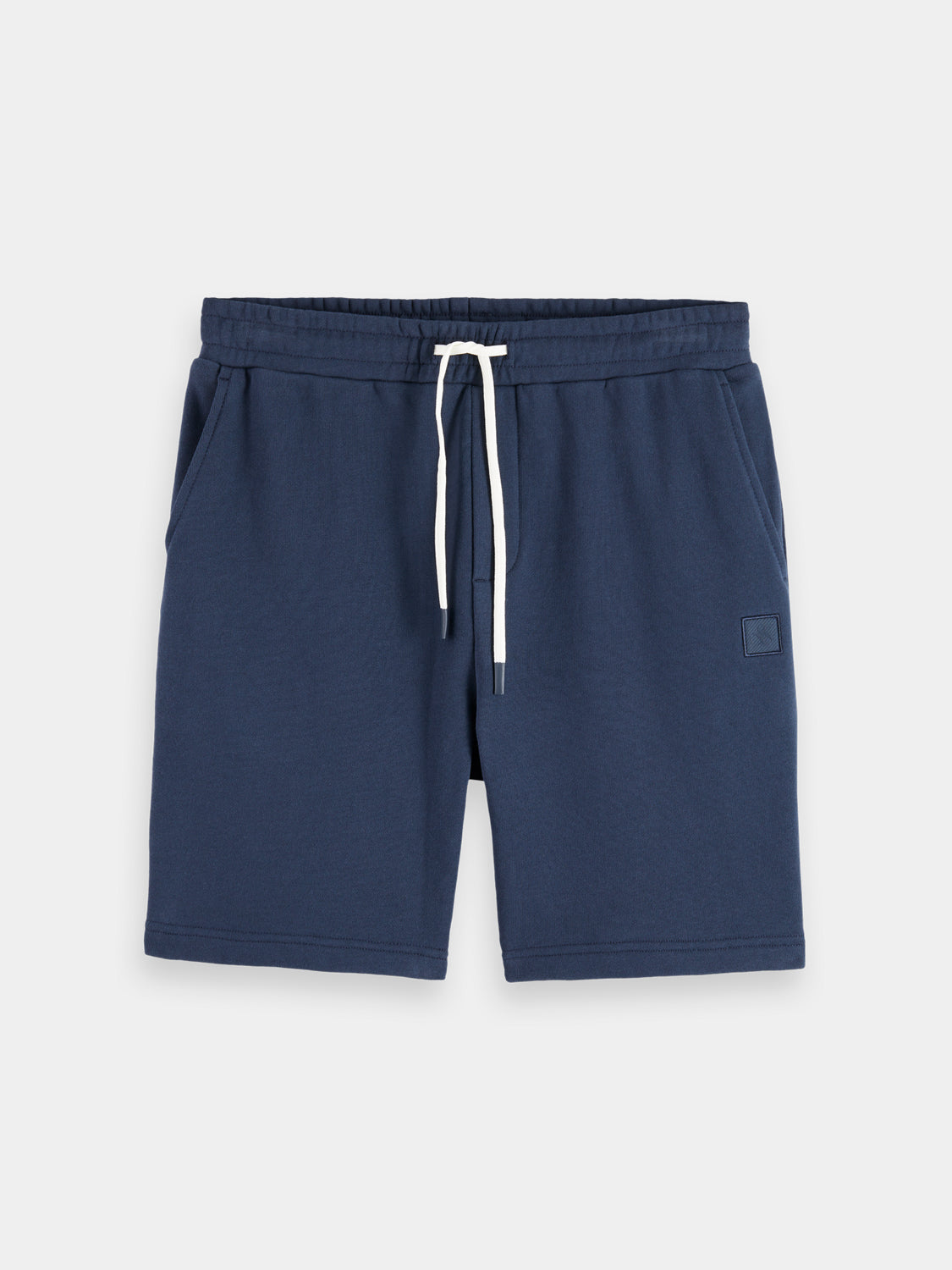 SCOTCH & SODA logo badge sweatshorts showing navy blue fabric with a branded logo patch on the leg.