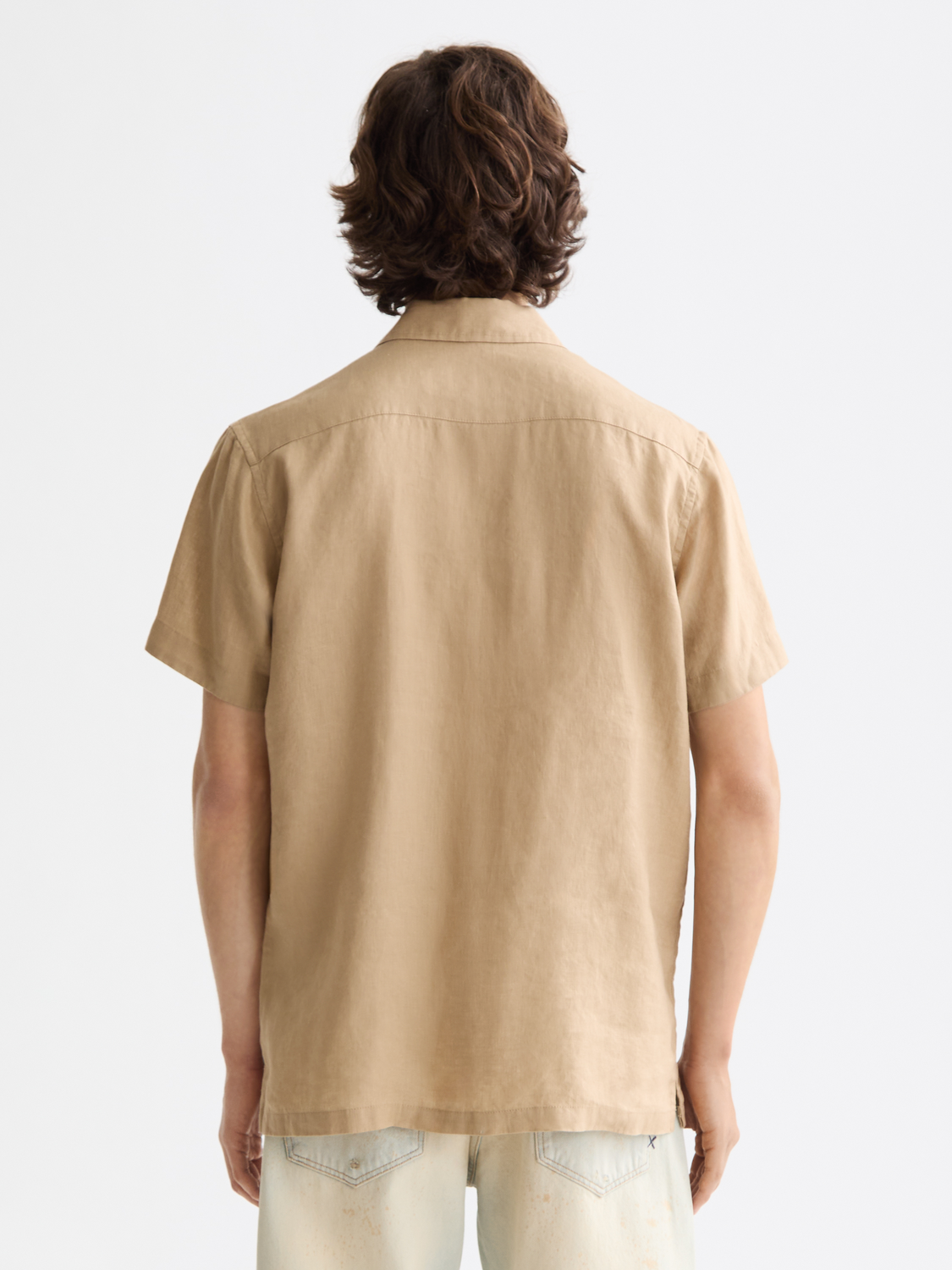 Short-sleeved linen shirt by Scotch & Soda, shown from the back in natural light, featuring a relaxed fit and lightweight fabric.