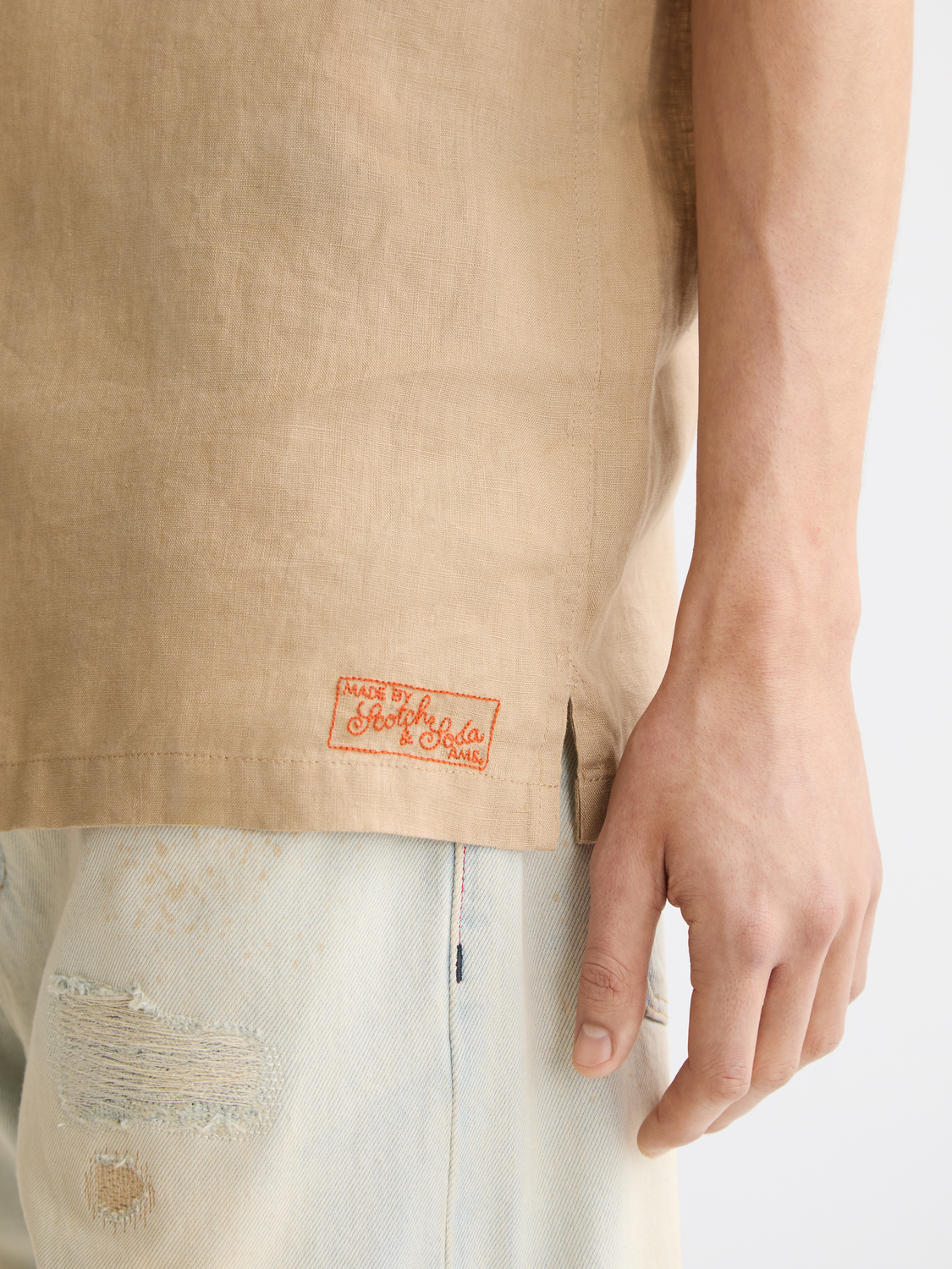 Light beige short-sleeved linen shirt by Scotch & Soda, showing a relaxed fit with a classic collar and button front.