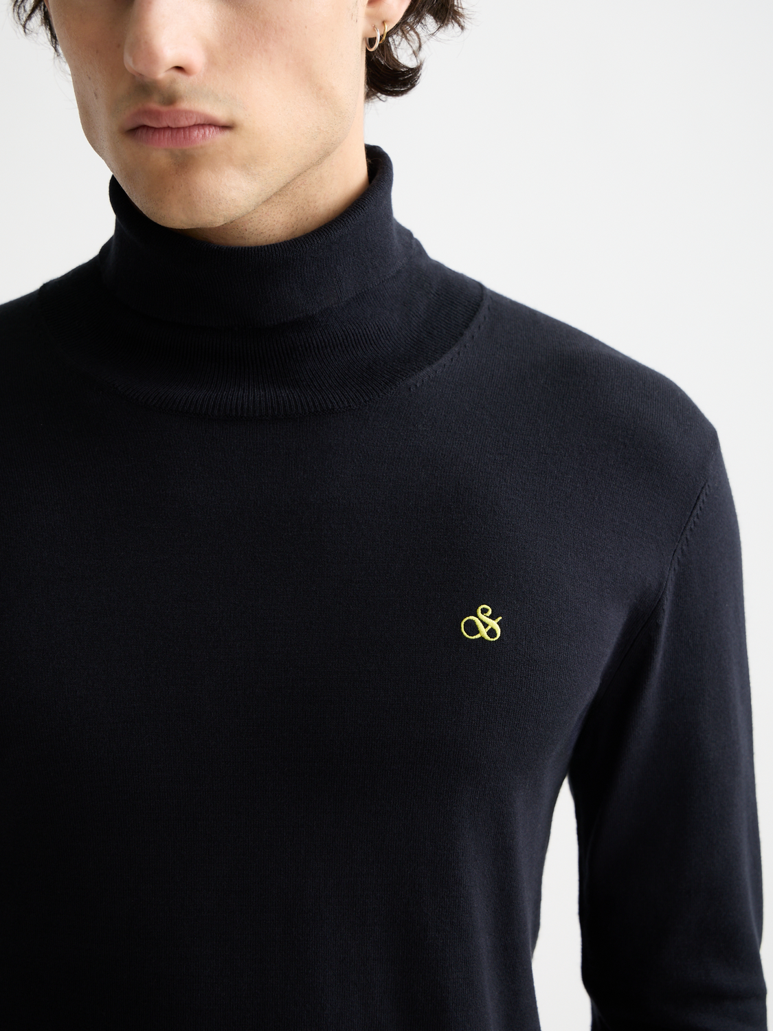Close-up of a navy blue Scotch & Soda knit turtleneck sweater with ribbed collar and textured knit pattern.