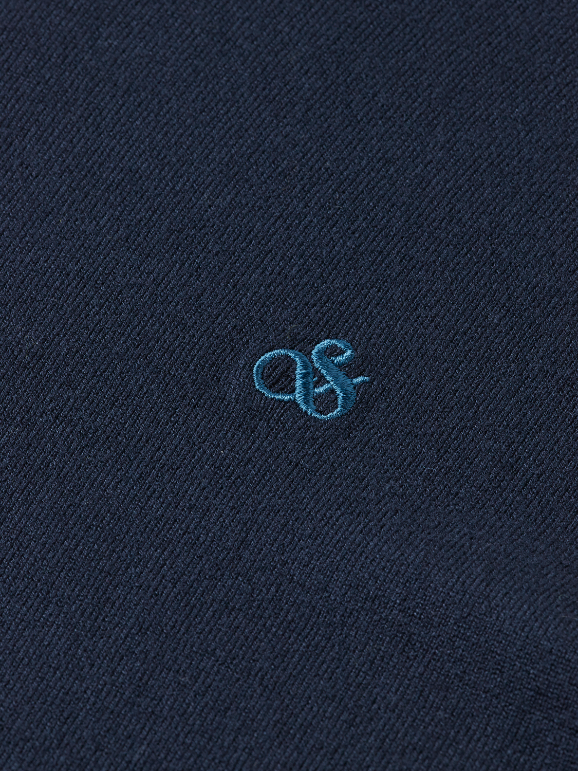 Close-up of a navy knit turtleneck sweater by Scotch & Soda, showcasing its textured knit fabric and high collar.