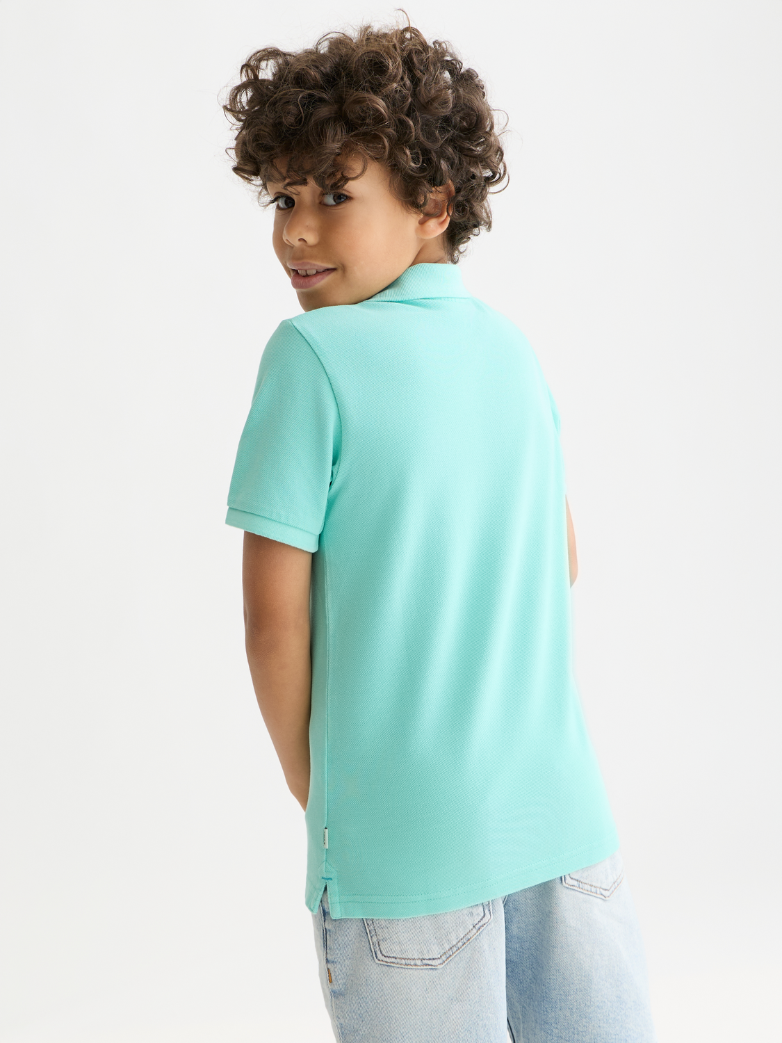 Kids' garment-dyed pique polo shirt by Scotch & Soda, showing back view with collar and short sleeves.