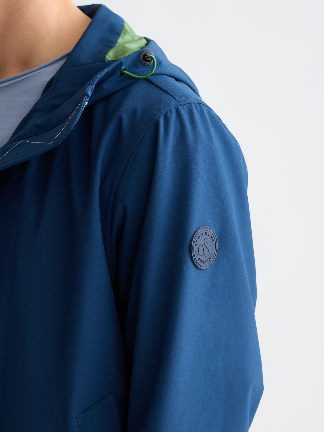 SCOTCH & SODA softshell hooded jacket with front zipper and adjustable drawstrings, shown in a close-up view.
