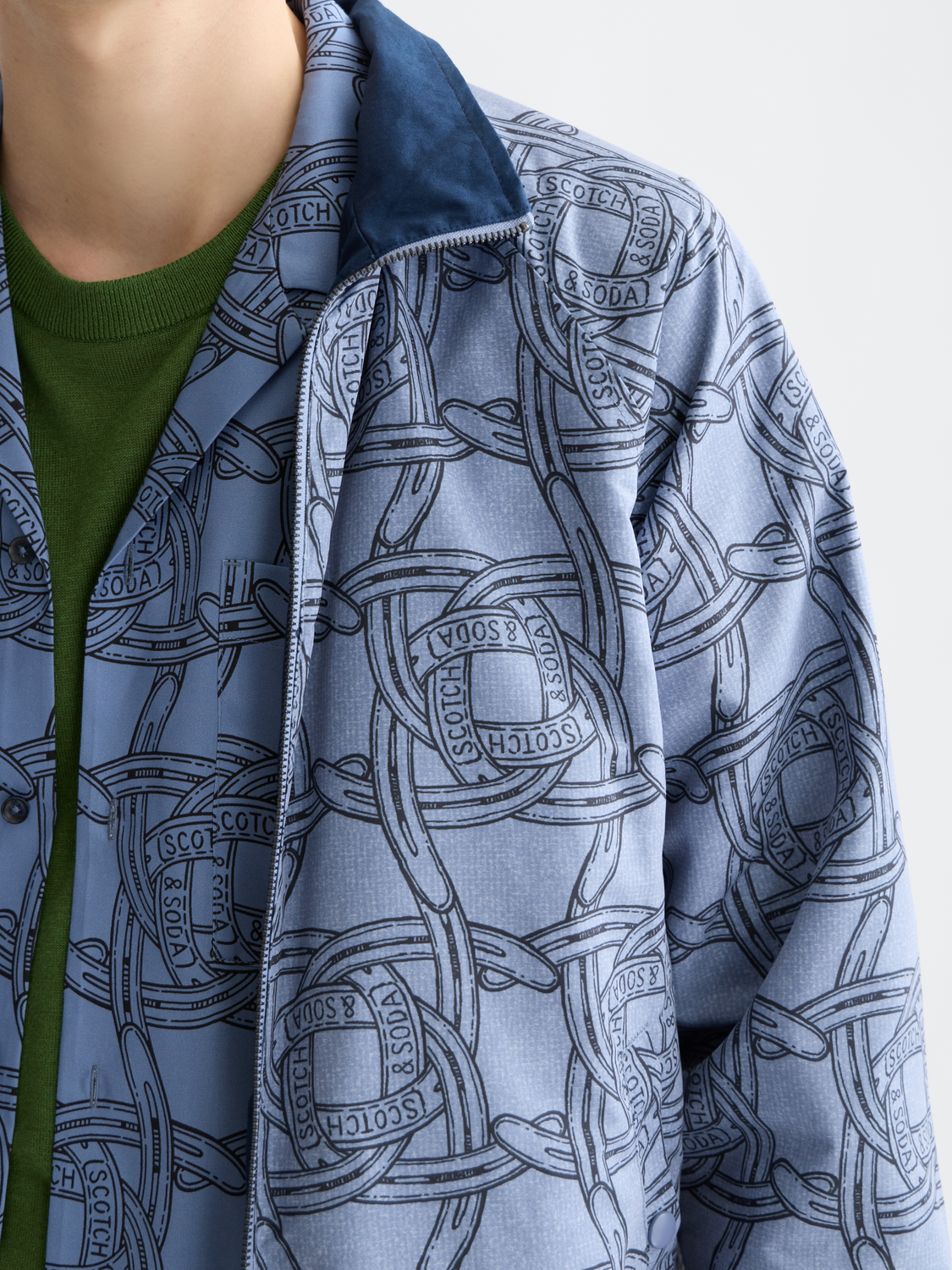 Reversible printed jacket by Scotch & Soda featuring vibrant patterns, shown with both sides visible in a stylish outdoor setting.