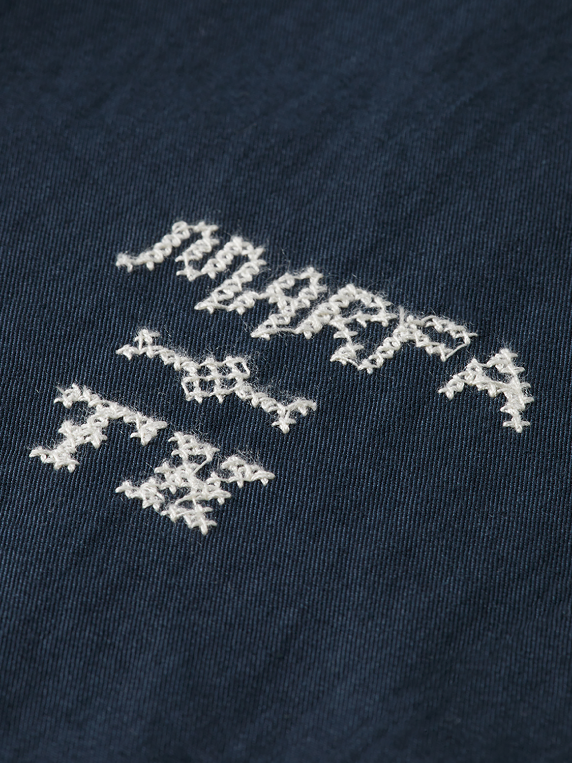 Embroidery detail on stylish Scotch & Soda chinos pants, showcasing classic design and tailored fit.