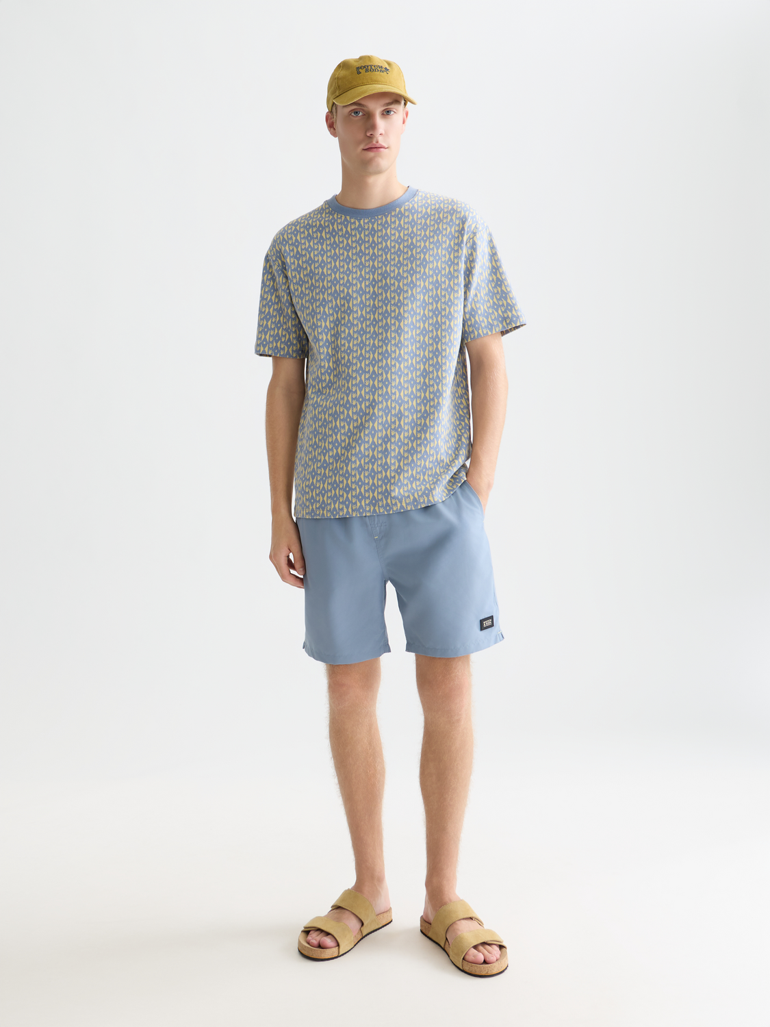 Mid-length SCOTCH & SODA swimshorts in vibrant print, displayed on a hanger showcasing their stylish design and lightweight fabric.