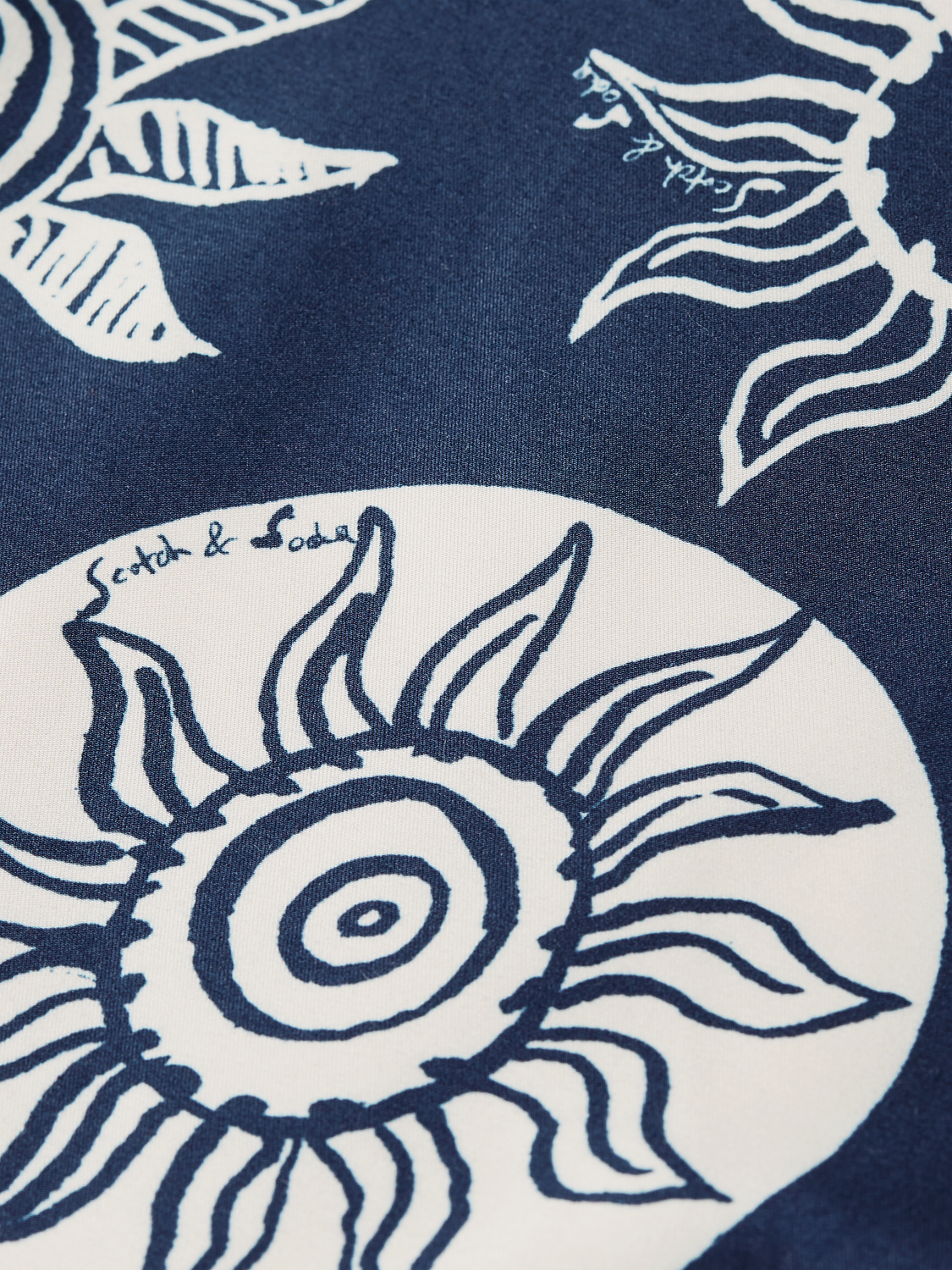 Printed swimshorts by Scotch & Soda featuring vibrant tropical patterns, displayed laid flat on a white background.