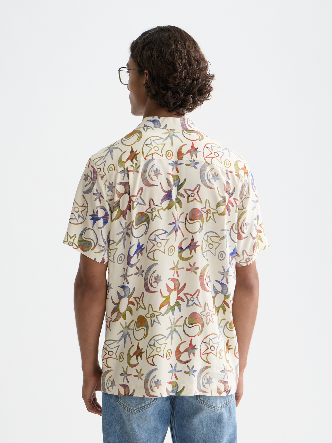 Printed short-sleeved shirt by Scotch & Soda with vibrant pattern, displayed on a hanger against a neutral background.