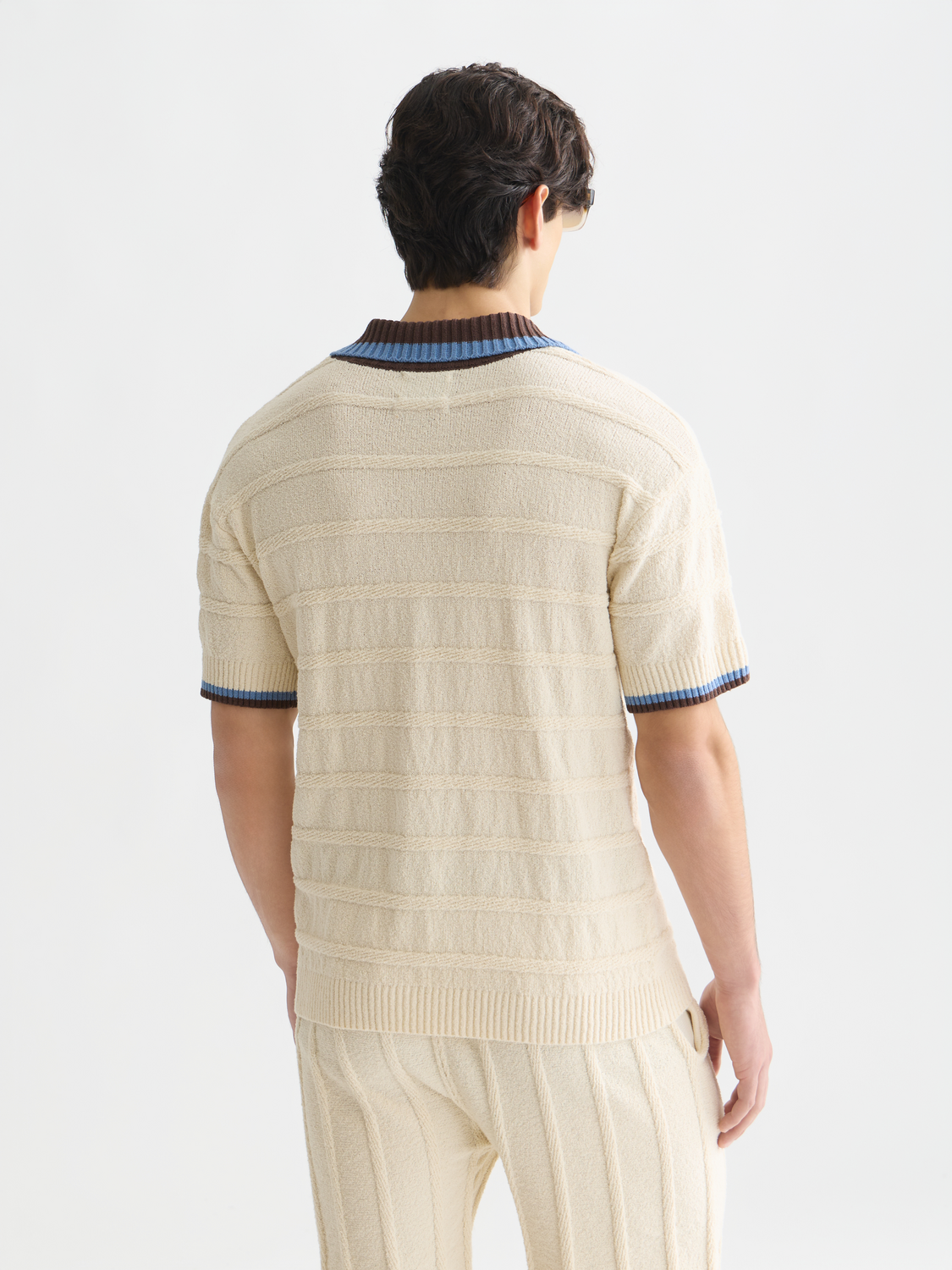 Knitted SCOTCH & SODA polo shirt in coral color, back view showing textured fabric and classic collar detail.